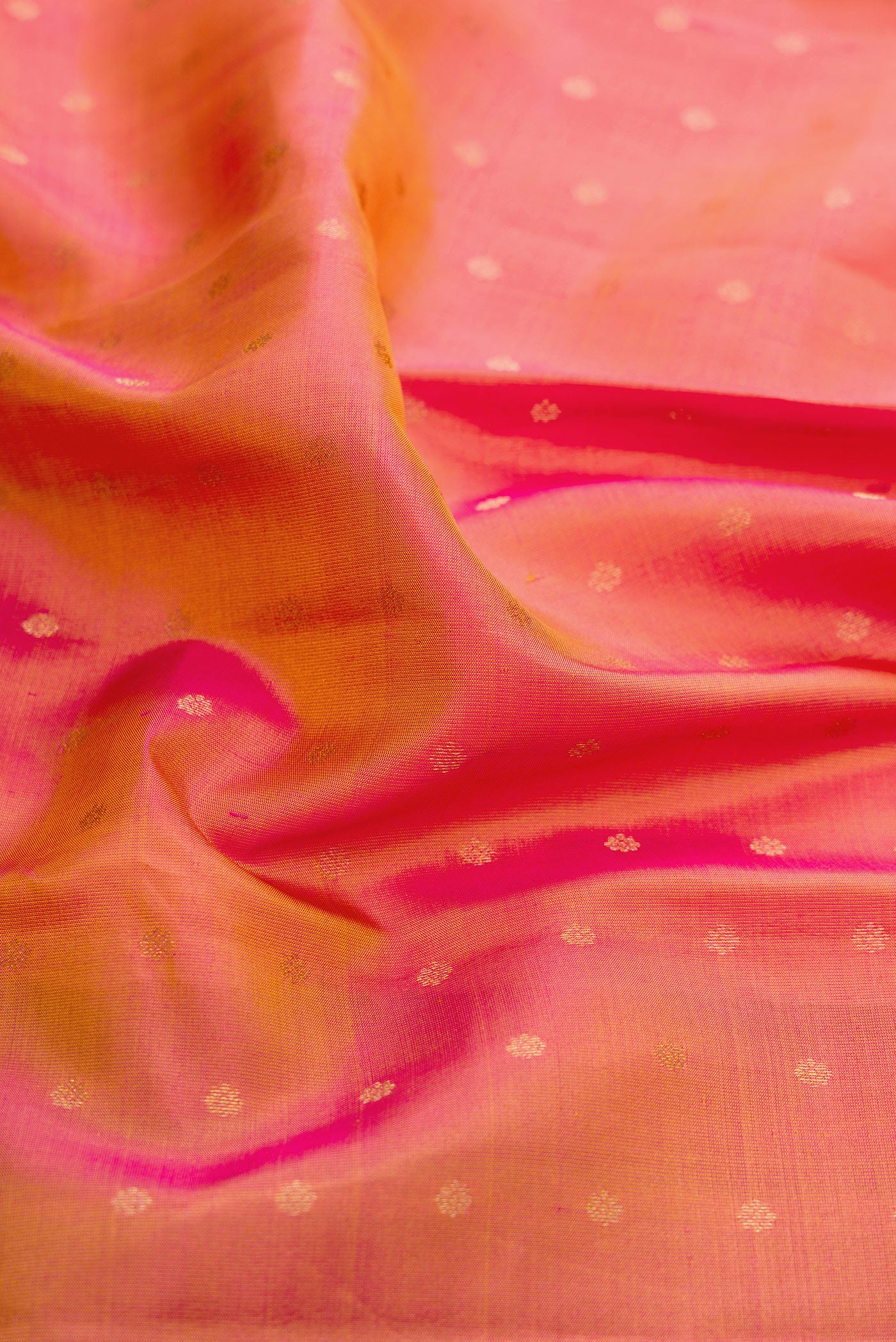 Close up of Coral Dual Tone Kanchipuram Silk Saree with Zari Butta on the body and Zari And Thread Border.  displaying folds