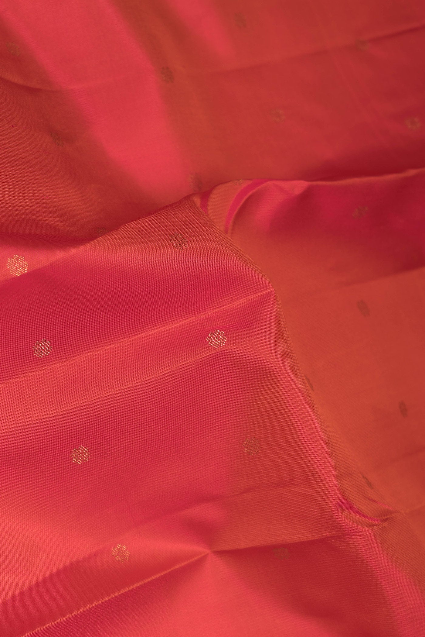 Close up of Orange Dual Tone Kanchipuram Silk Saree with Zari Butta on the body and Zari Border.  displaying folds