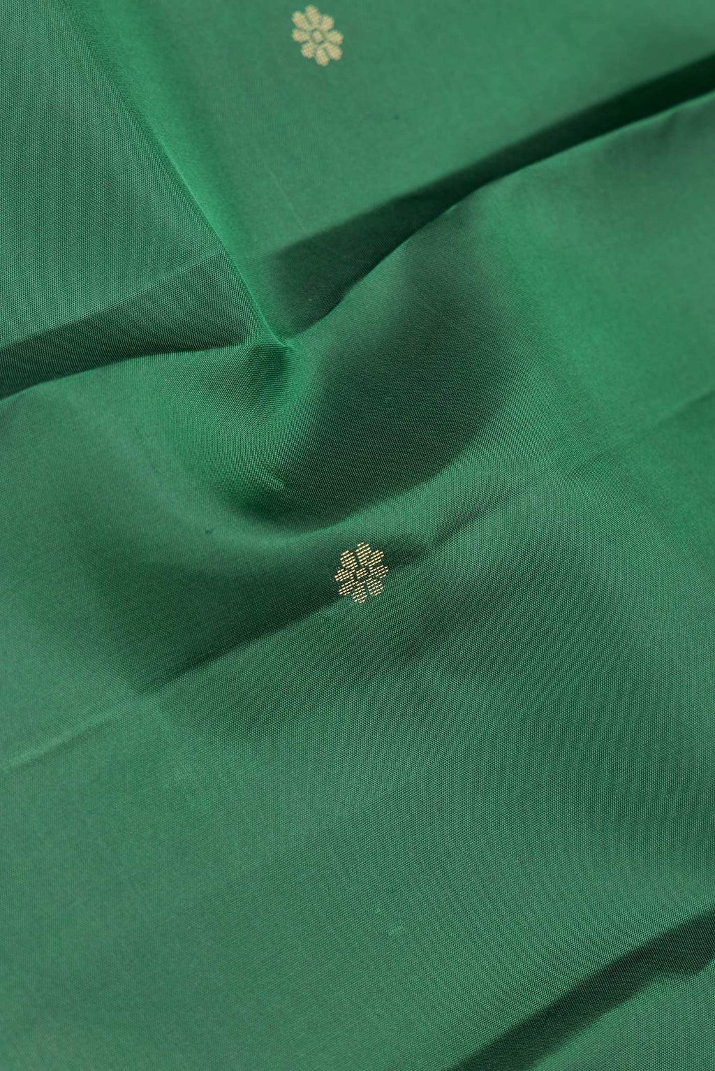 Close up of Green Dual Tone Kanchipuram Silk Saree with Zari Butta on the body and Zari Border.  displaying folds