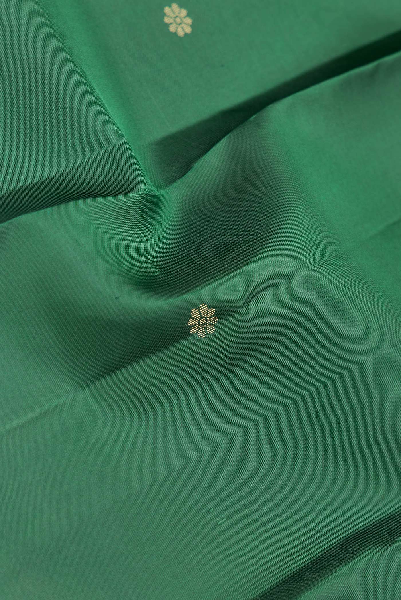 Close up of Green Dual Tone Kanchipuram Silk Saree with Zari Butta on the body and Zari Border.  displaying folds