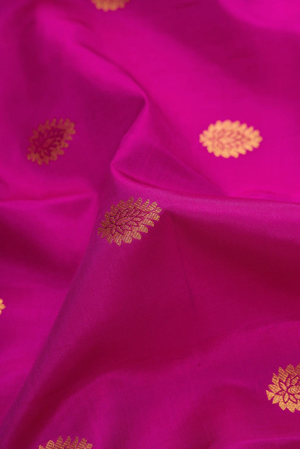 Close up of Magenta Dual Tone Kanjivaram Silk Saree with Zari Butta on the body and Zari Border.  displaying folds
