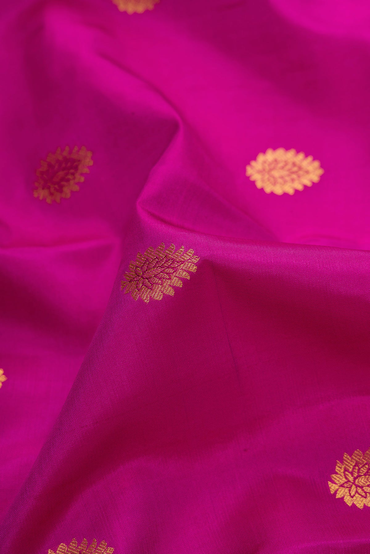 Close up of Magenta Dual Tone Kanjivaram Silk Saree with Zari Butta on the body and Zari Border.  displaying folds