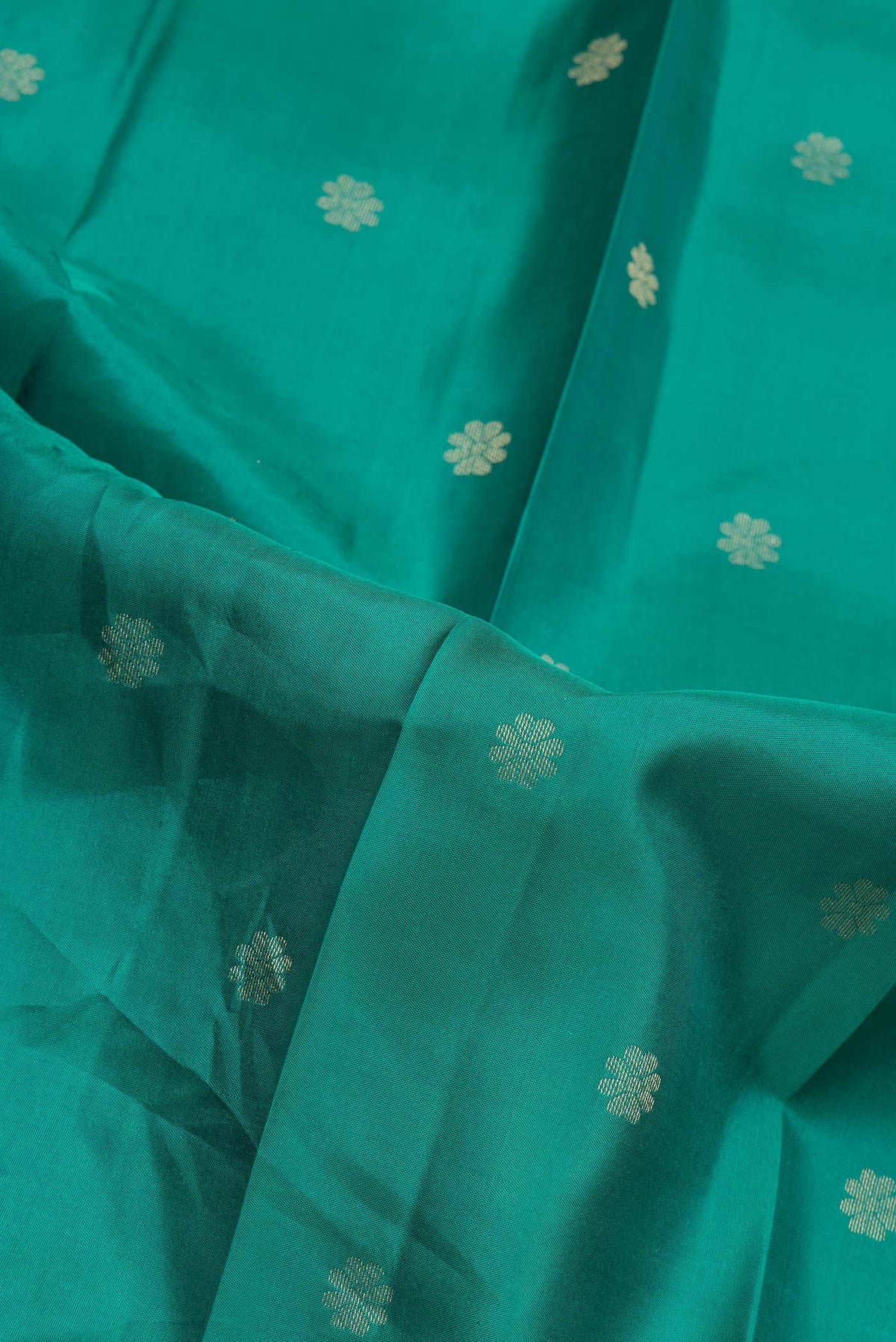 Close up of Green Dual Tone Kanjivaram Silk Saree with Zari Butta on the body and Zari Border.  displaying folds