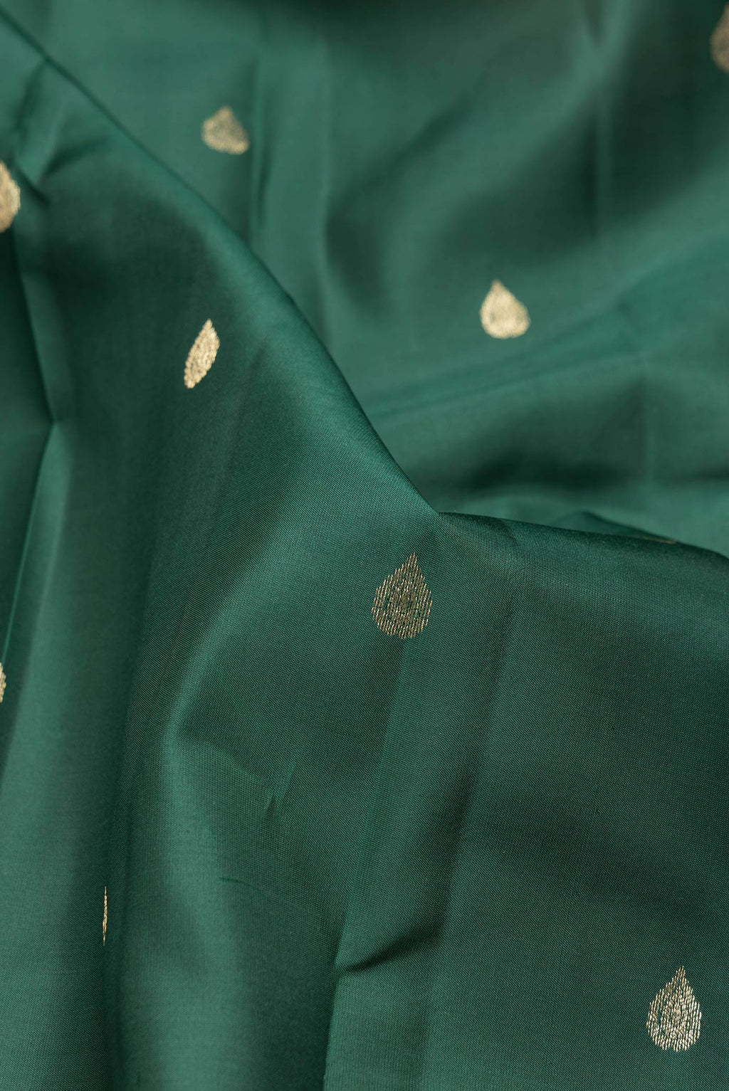 Close up of Green Dual Tone Kanchipuram Silk Saree with Zari Butta on the body and Zari Border.  displaying folds