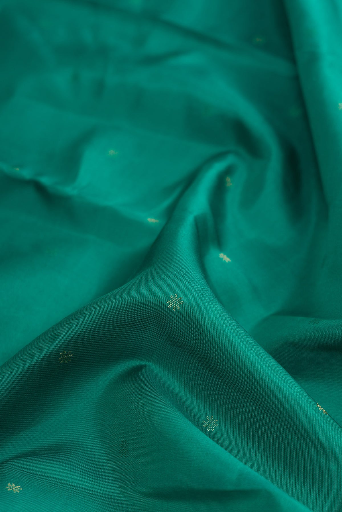 Close up of Green Dual Tone Kanchipuram Silk Saree with Zari Butta on the body and Zari Border.  displaying folds