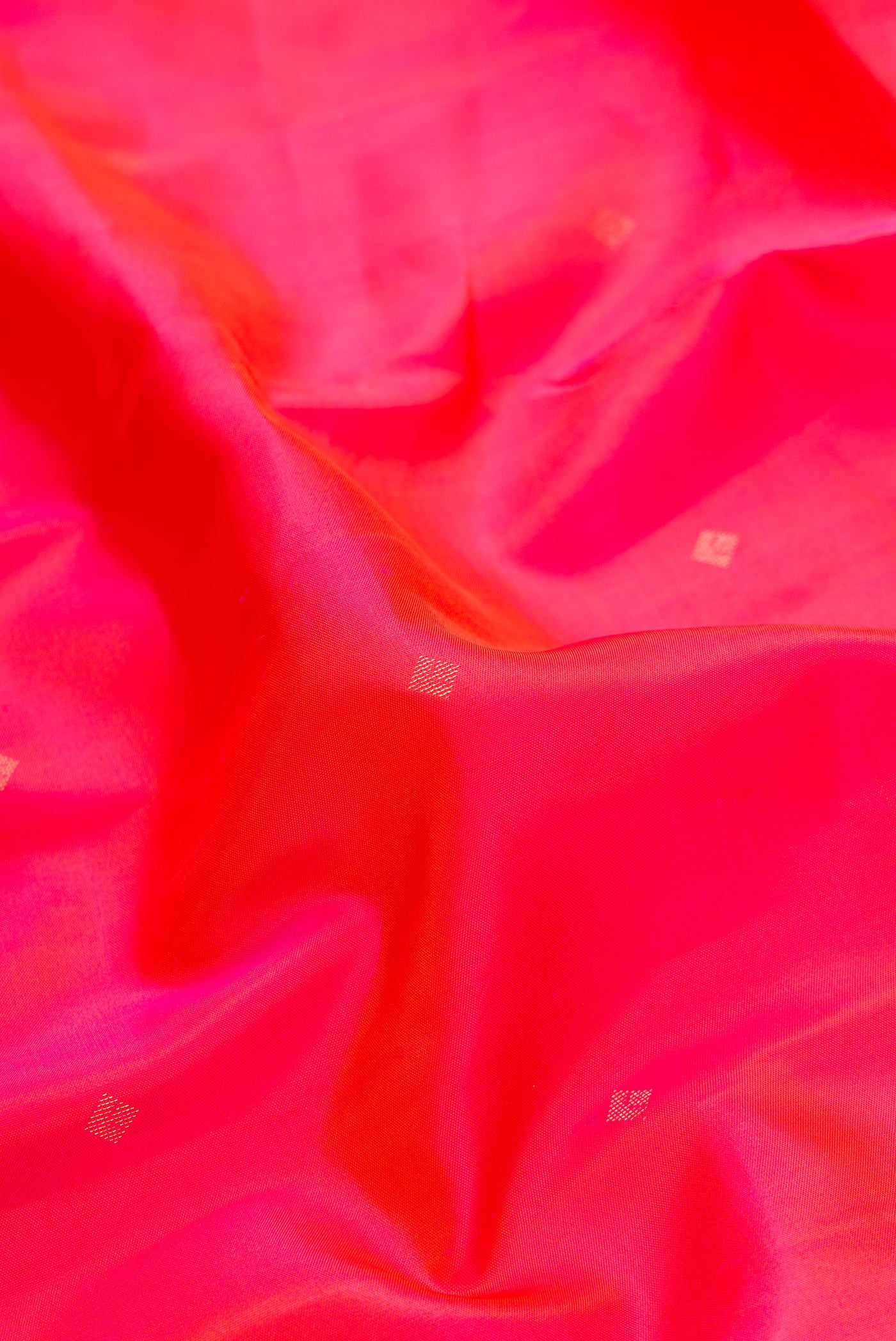 Close up of Coral Dual Tone Kanchipuram Silk Saree with Zari Butta on the body and Zari Border.  displaying folds