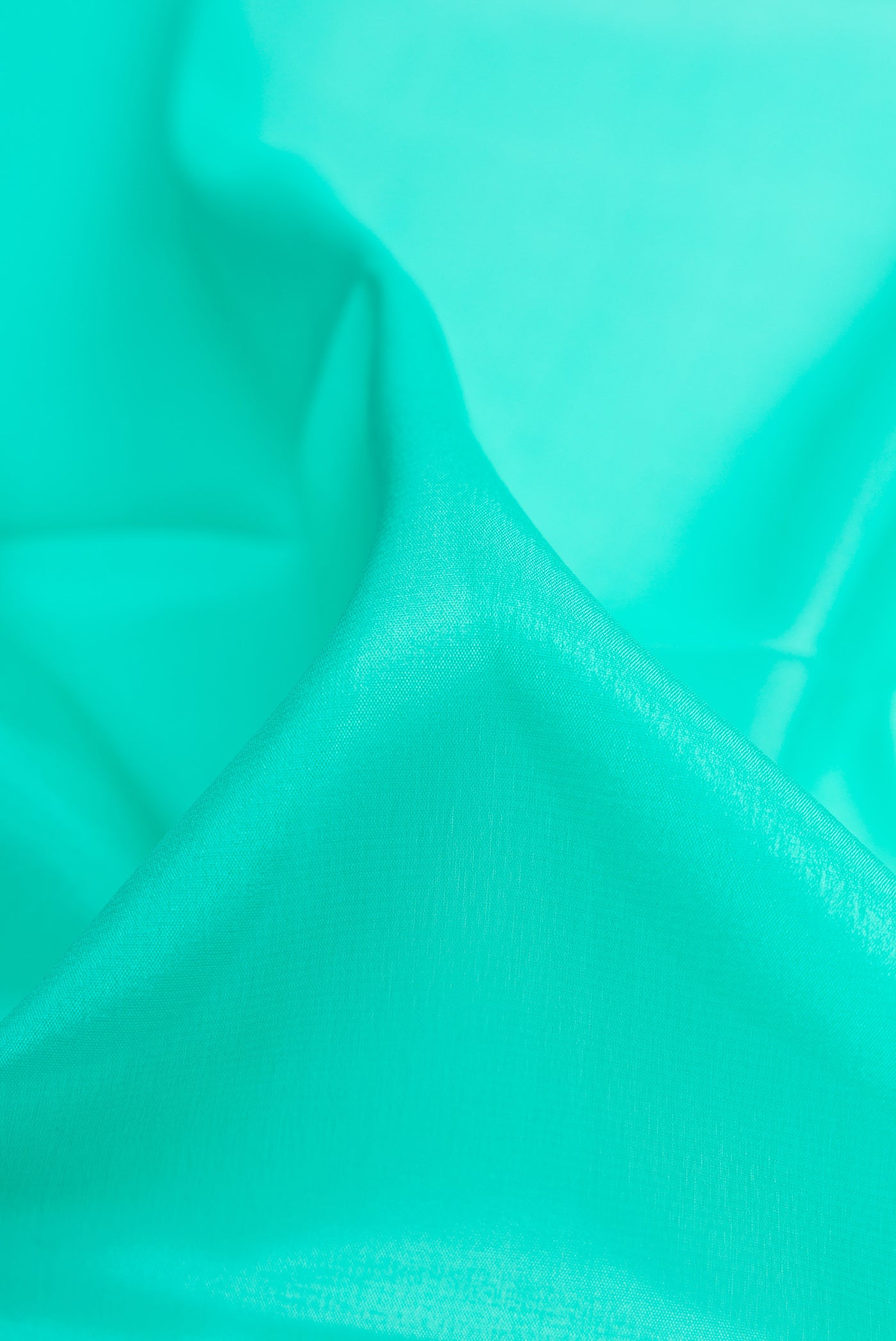 Close up of Sea Green Mysore Crepe Saree with Plain Body and Zari Border.  displaying folds