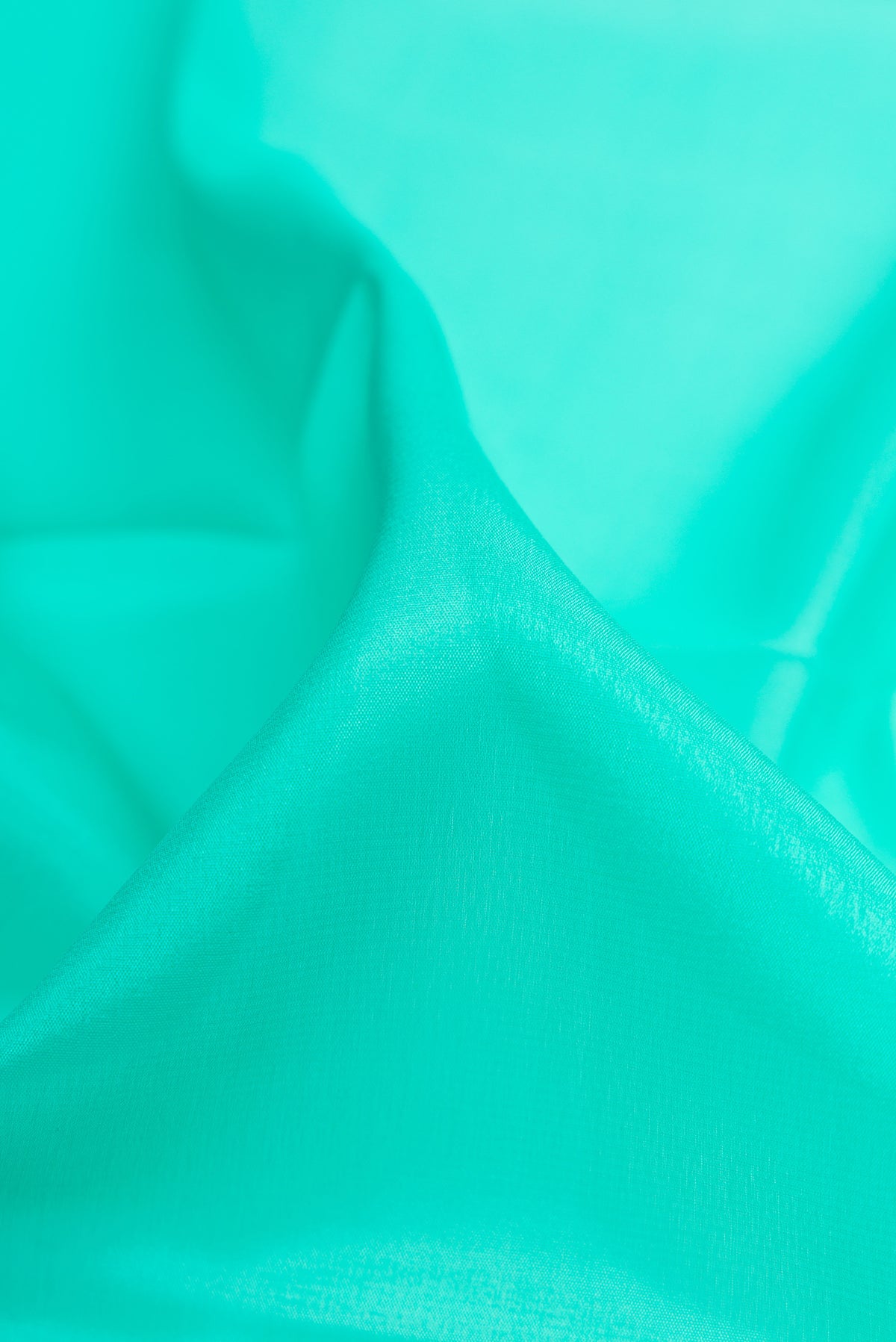 Close up of Sea Green Mysore Crepe Saree with Plain Body and Zari Border.  displaying folds