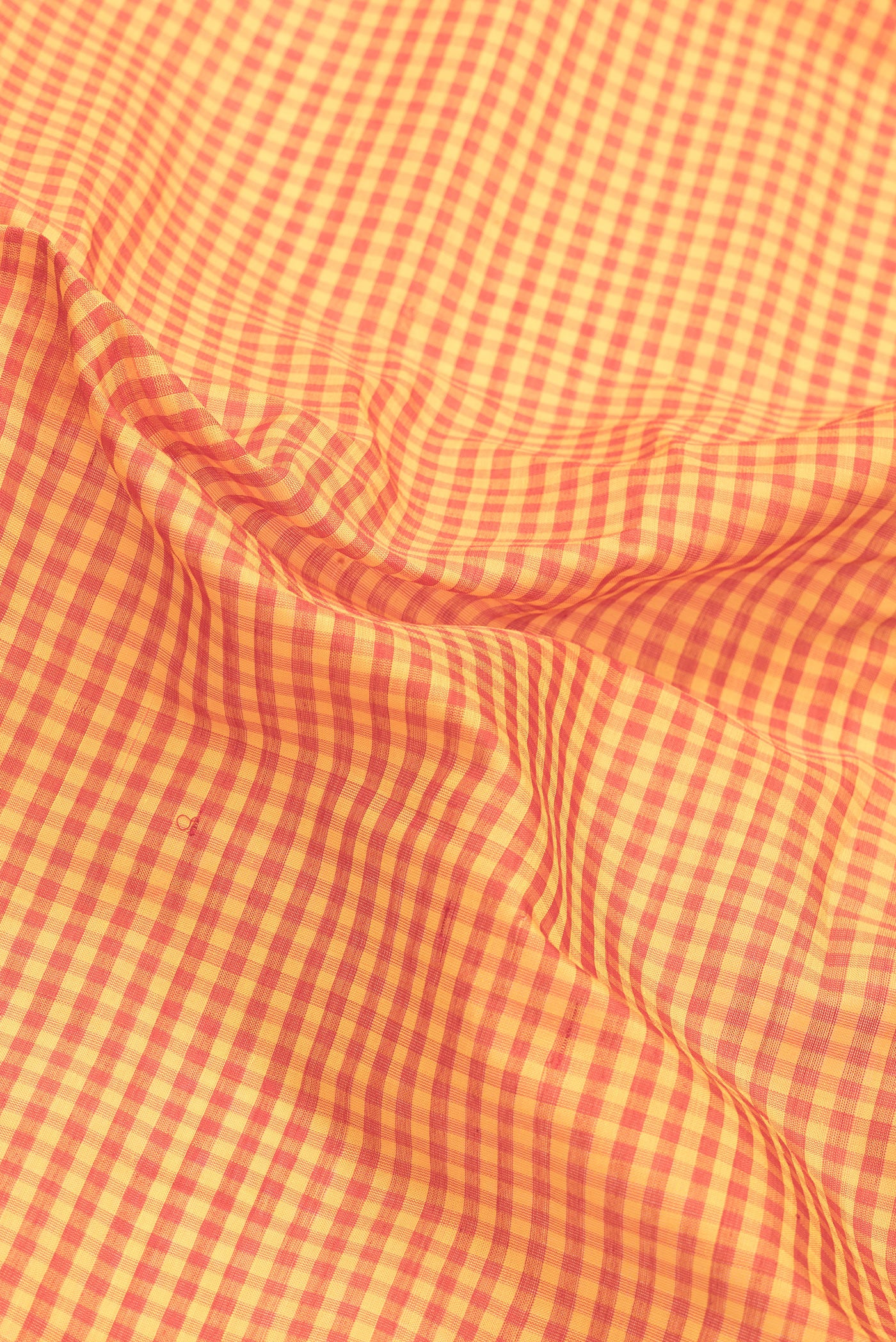 Close up of Orange Dual Tone Gadwal Silk Saree with Checked design on the body and Zari Border.  displaying folds