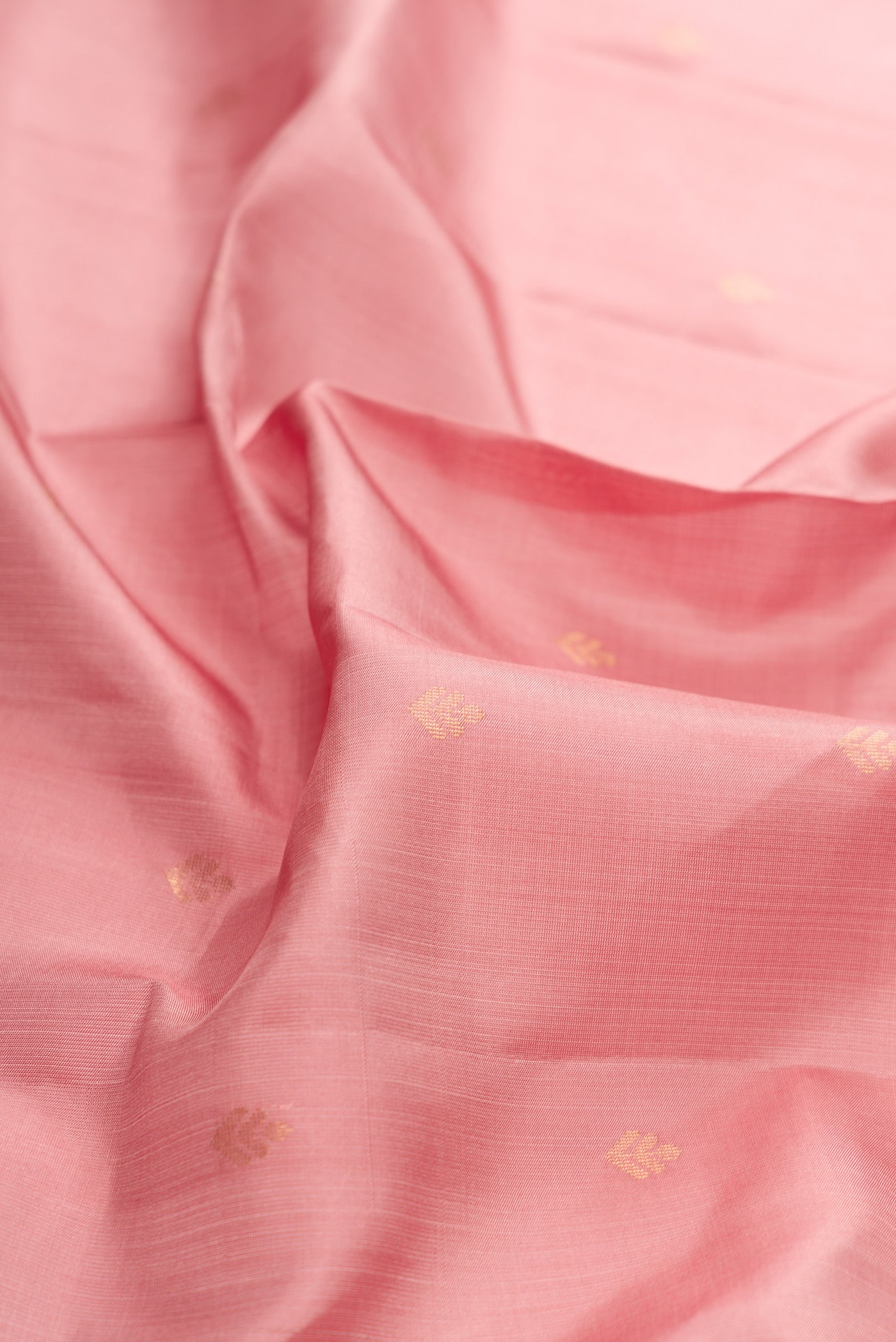 Close up of Rose Gold Dual Tone Soft Silk Saree with Zari Butta on the body and Zari Border.  displaying folds