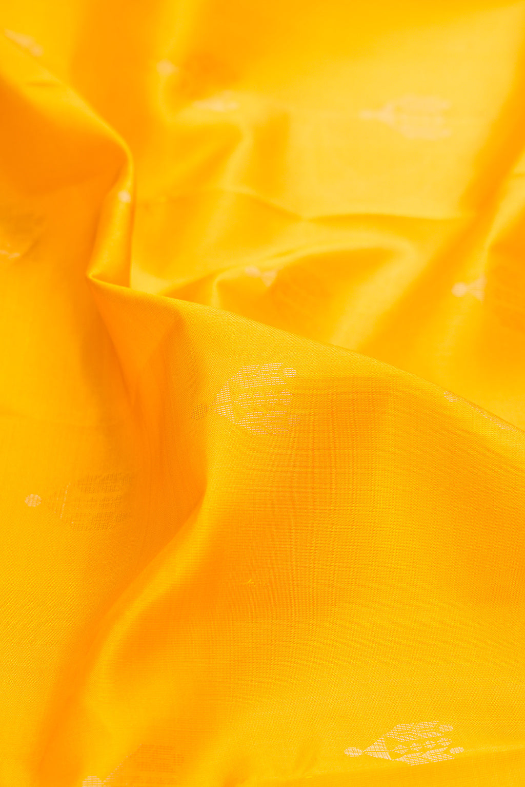 Close up of Yellow Dual Tone Soft Silk Saree with Zari Butta on the body and Zari Border.  displaying folds