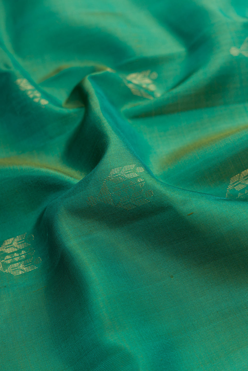 Close up of Green Dual Tone Soft Silk Saree with Zari Butta on the body and Zari Border.  displaying folds