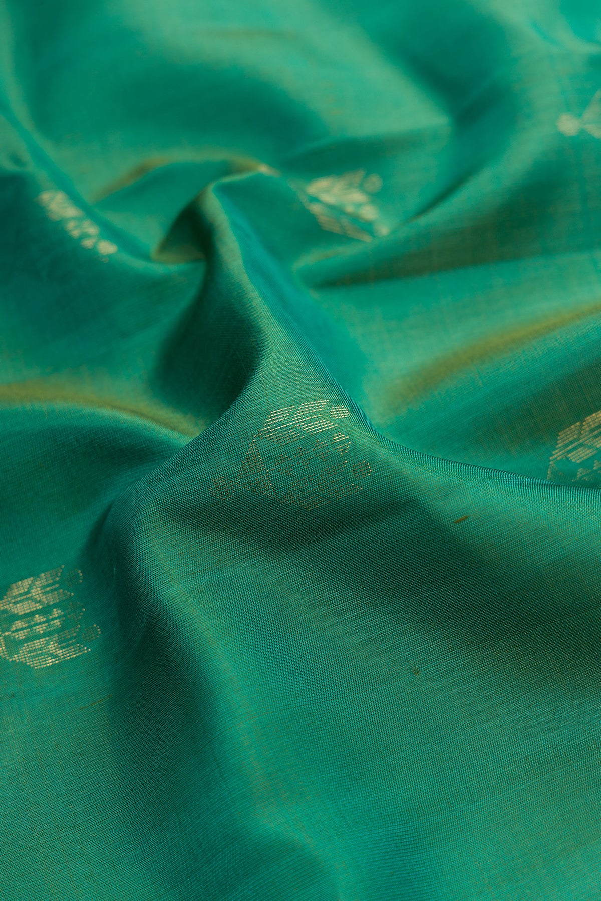 Close up of Green Dual Tone Soft Silk Saree with Zari Butta on the body and Zari Border.  displaying folds