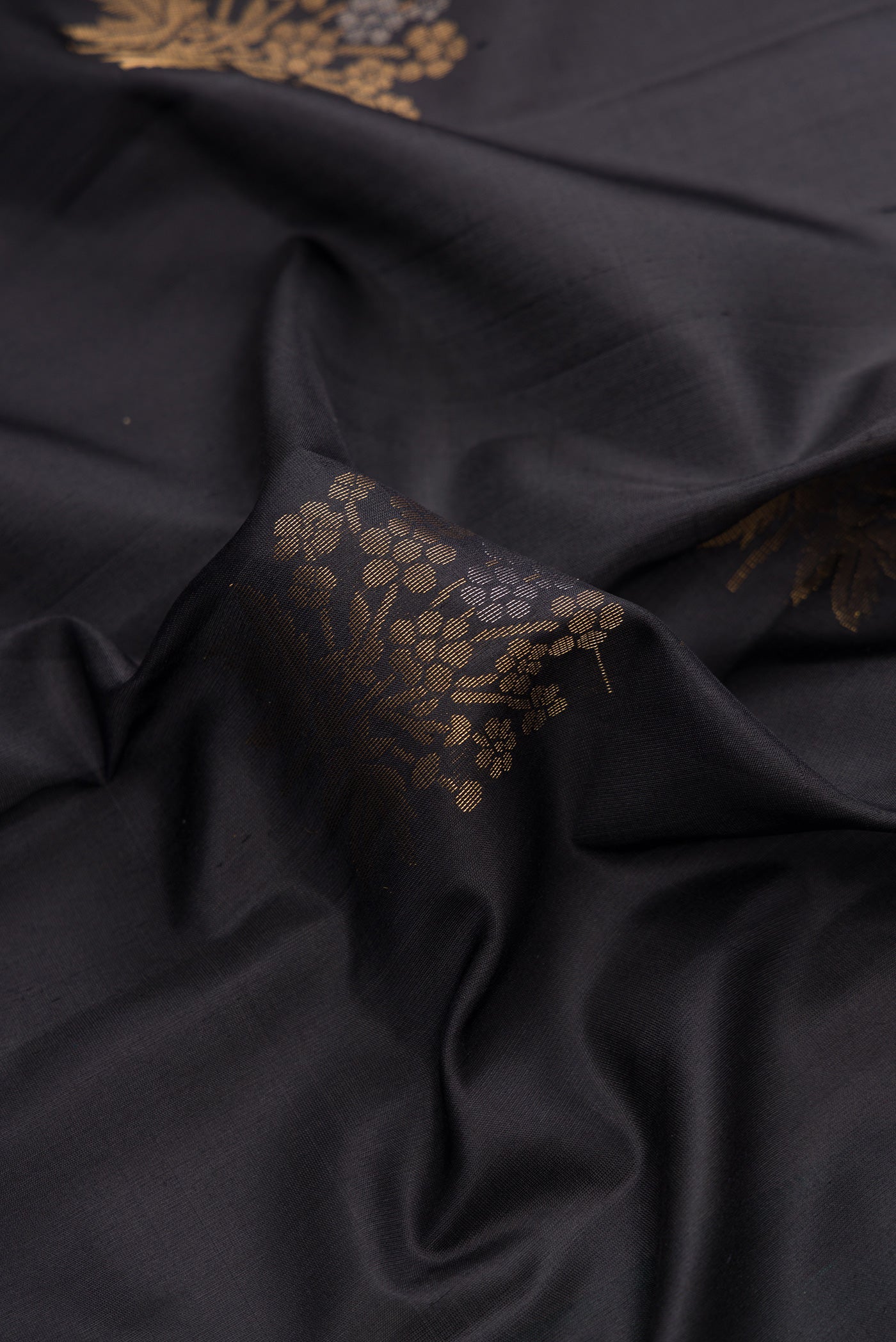 Close up of Black Dual Tone Soft Silk Saree with Zari Butta on the body and Zari Border.  displaying folds