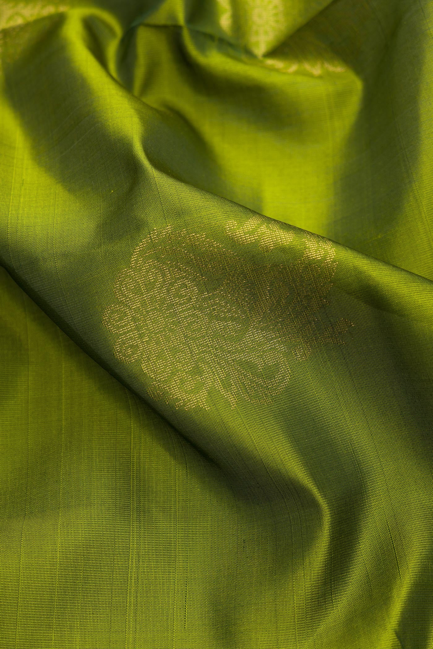 Close up of Green Dual Tone Soft Silk Saree with Zari Butta on the body and Zari Border.  displaying folds