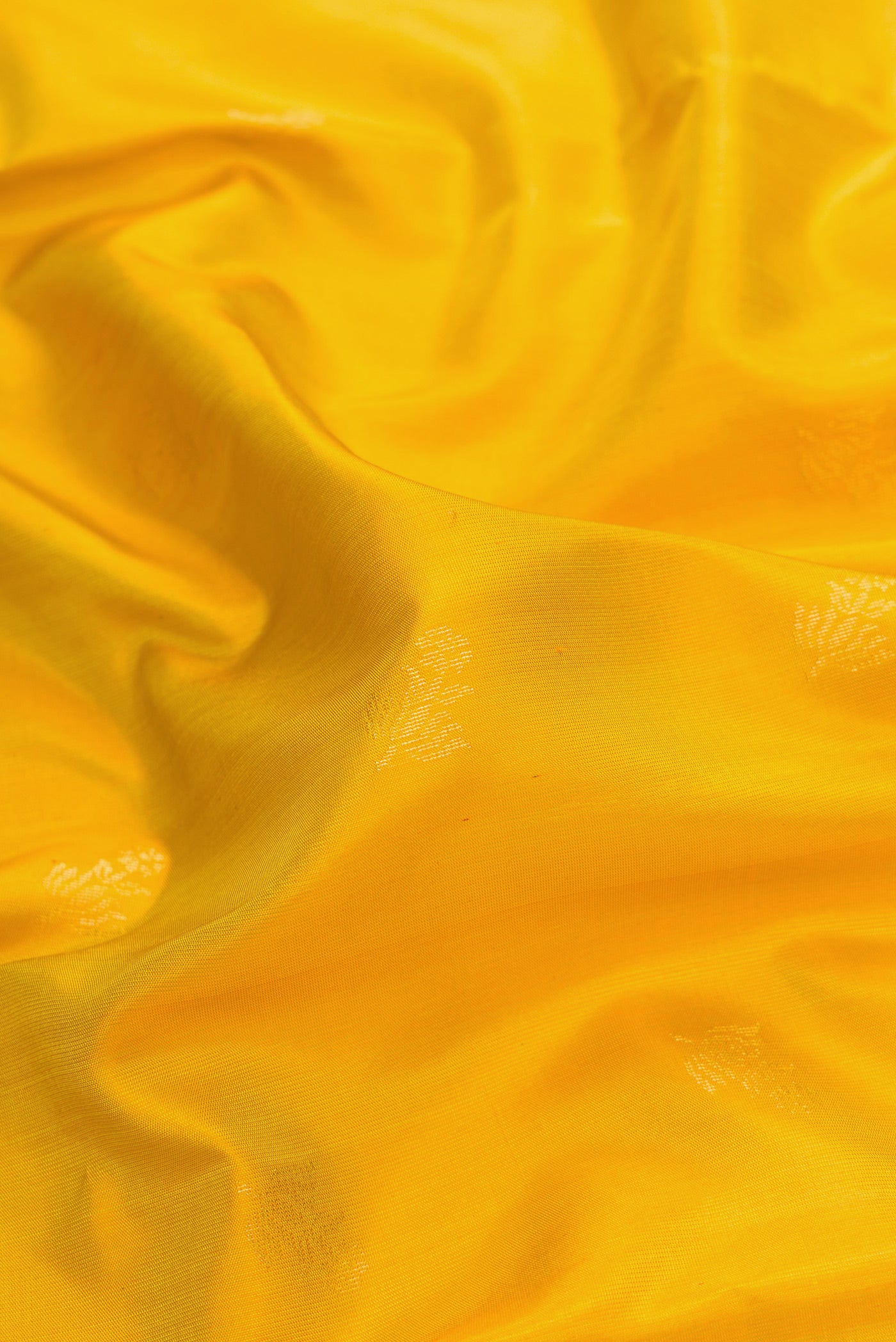 Close up of Yellow Dual Tone Soft Silk Saree with Zari Butta on the body and Zari Border.  displaying folds