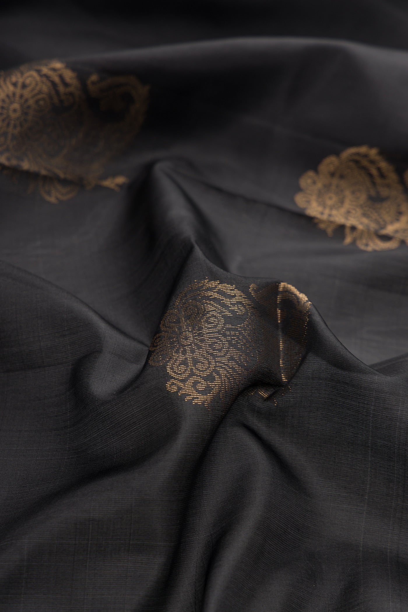 Close up of Black Dual Tone Soft Silk Saree with Zari Butta on the body and Zari Border.  displaying folds