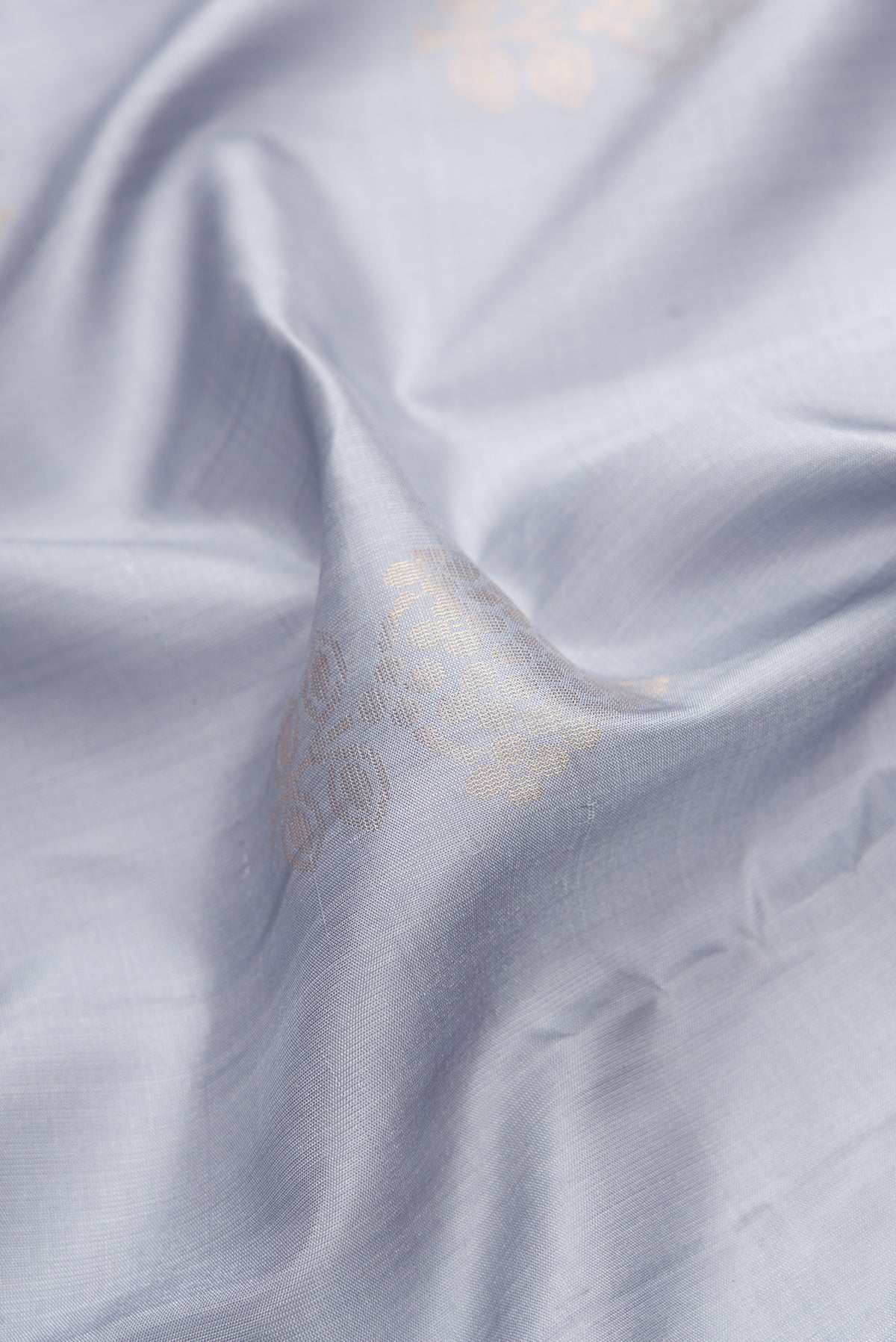 Close up of Grey Dual Tone Soft Silk Saree with Zari Butta on the body and Zari Border.  displaying folds