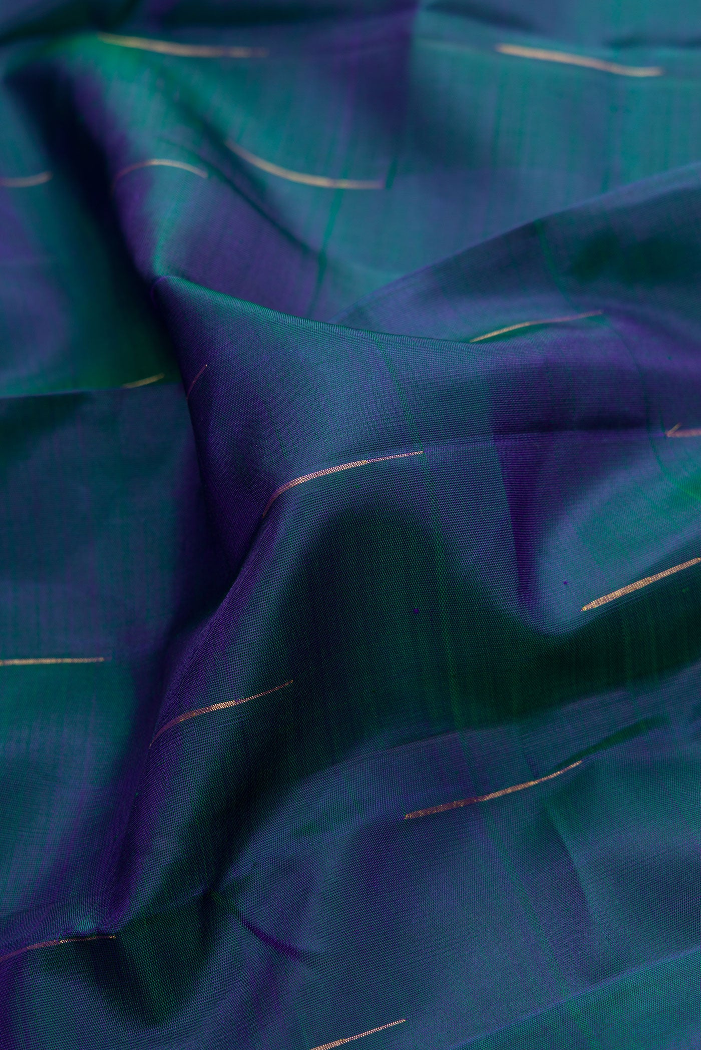 Close up of Peacock Blue Dual Tone Kanjivaram Silk Saree with Zari Butta on the body and Thin Zari Line.  displaying folds