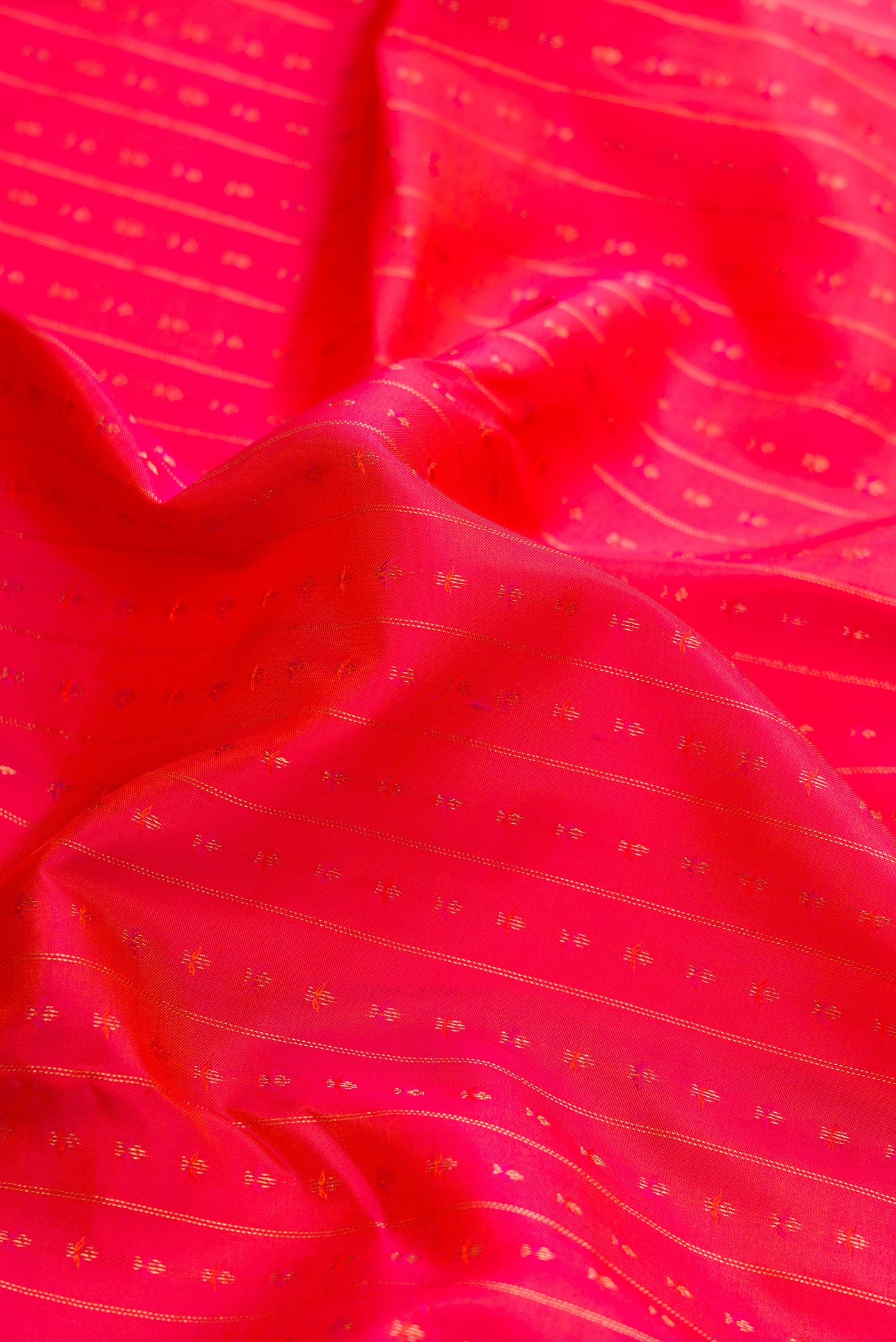 Close up of Orange Dual Tone Kanchipuram Silk Saree with Zari Butta on the body and Zari Border.  displaying folds