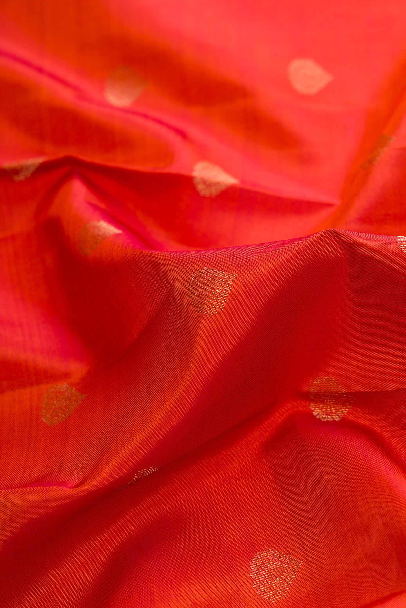 Close up of Brick Orange Dual Tone Kanchipuram Silk Saree with Zari Butta on the body and Zari Border.  displaying folds