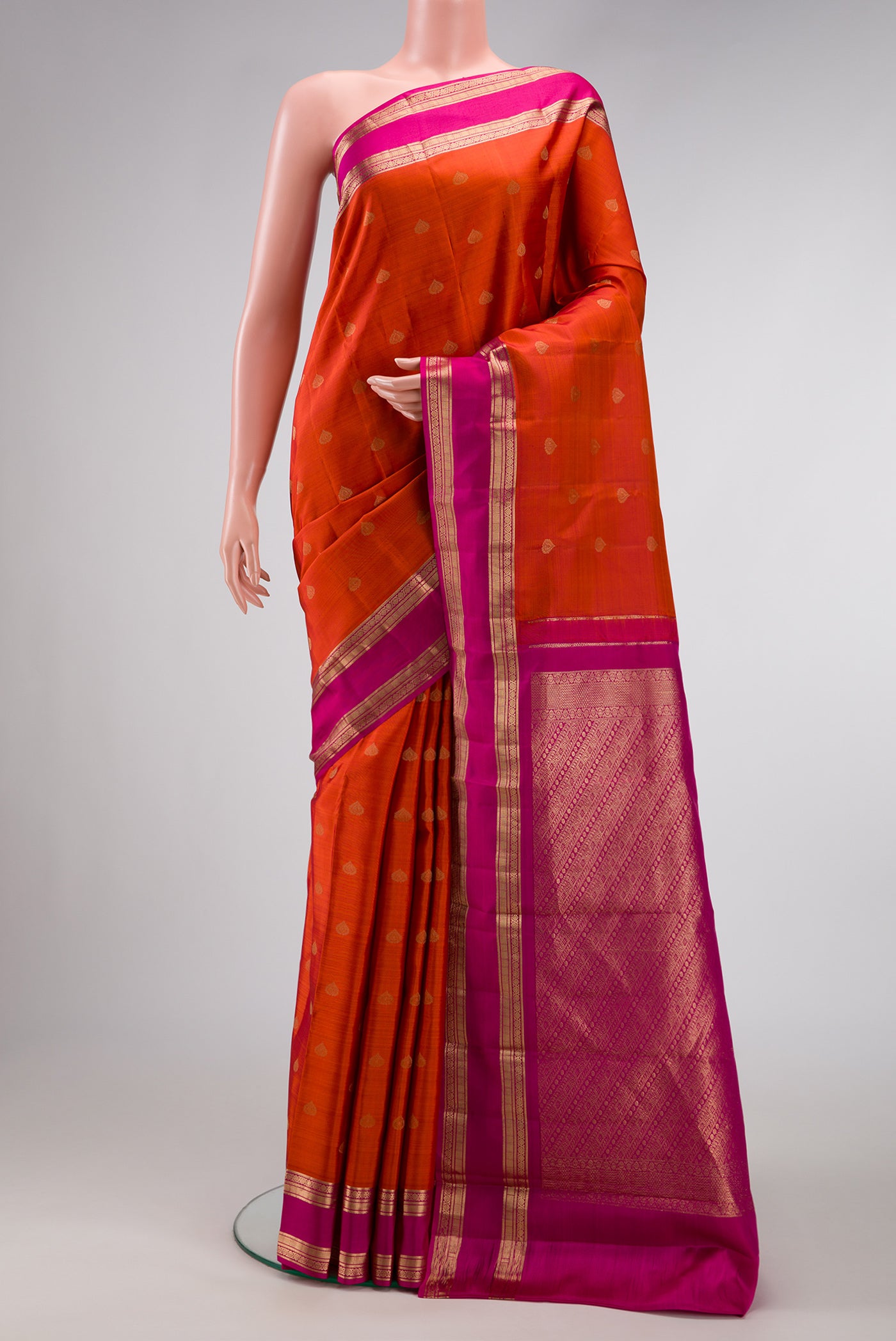 Brick Orange Dual Tone Kanchipuram Silk Saree with Zari Butta on the body and Zari Border.  displayed on a mannequin