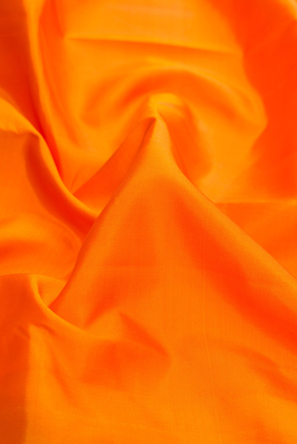Close up of Orange Dual Tone Kanchipuram Silk Saree with Plain Body and Zari Border.  displaying folds