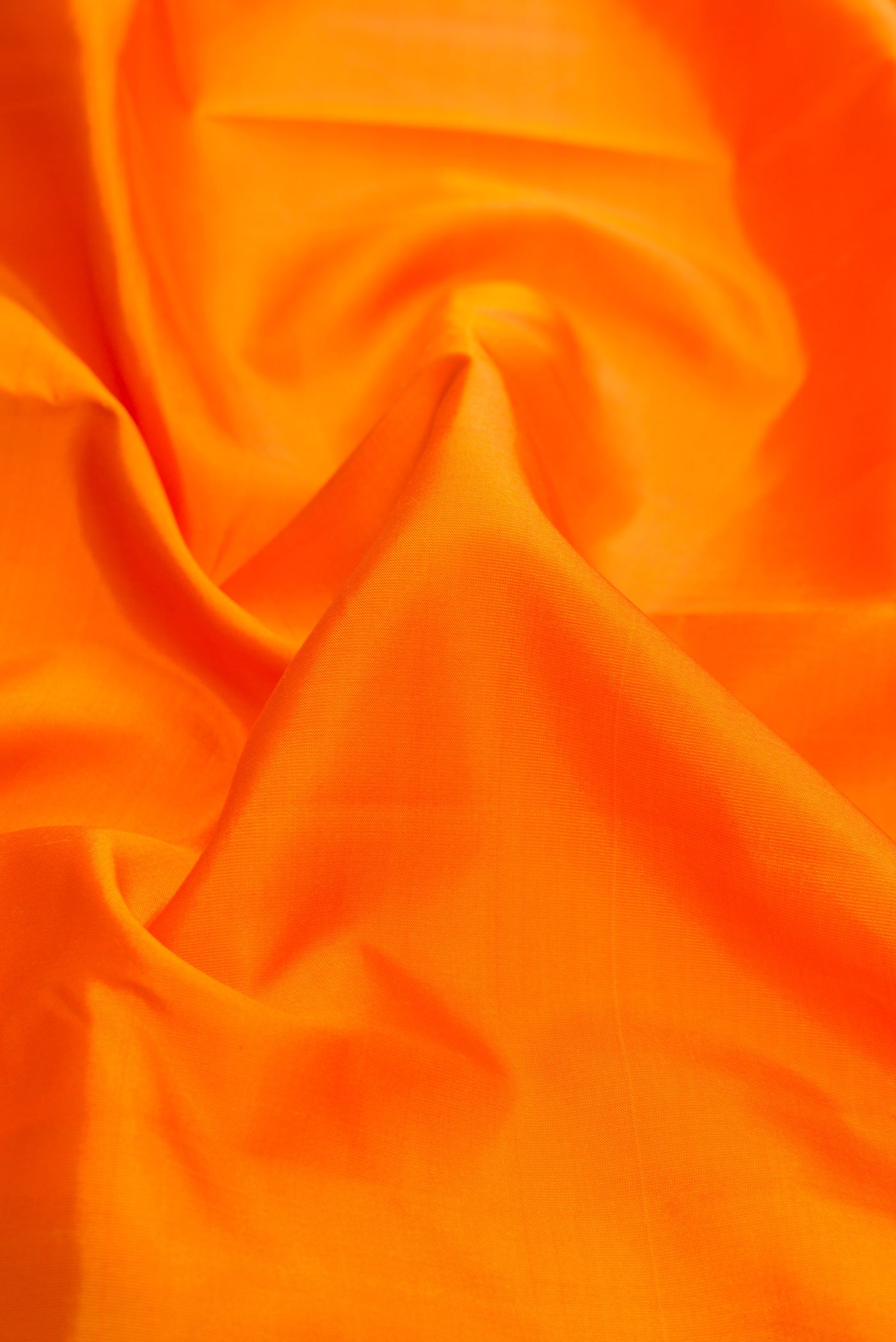 Close up of Orange Dual Tone Kanchipuram Silk Saree with Plain Body and Zari Border.  displaying folds