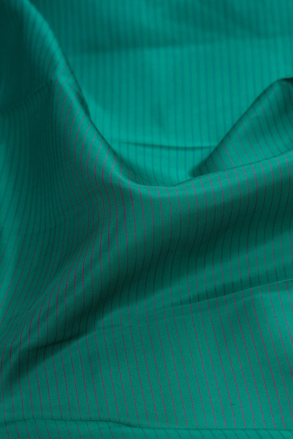 Close up of Green Dual Tone Kanchipuram Silk Saree with Stripes on the body and Zari Border.  displaying folds