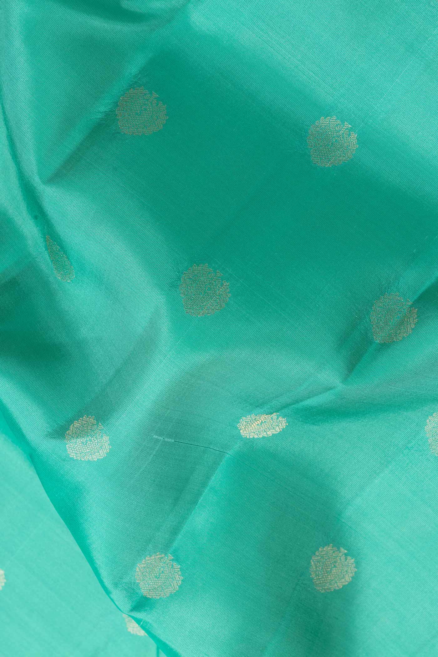 Close up of Sea Green Dual Tone Kanchipuram Silk Saree with Zari Butta on the body and Zari Border.  displaying folds