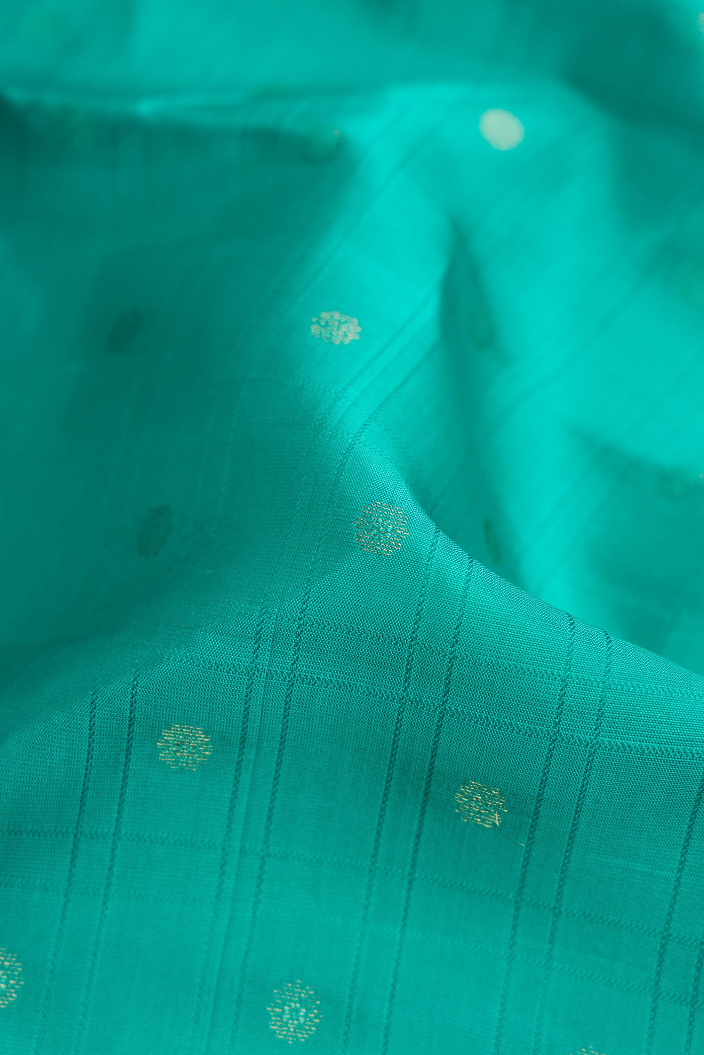 Close up of Sea Green Dual Tone Kanchipuram Silk Saree with Zari Butta on the body and Zari Border.  displaying folds