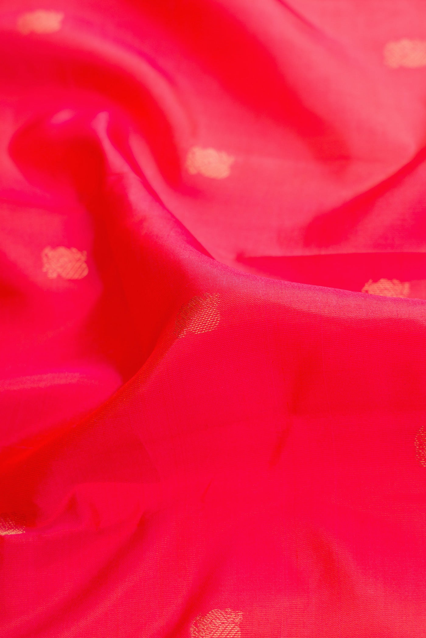 Close up of Coral Dual Tone Kanjivaram Silk Saree with Zari Butta on the body and Thin Zari Line.  displaying folds