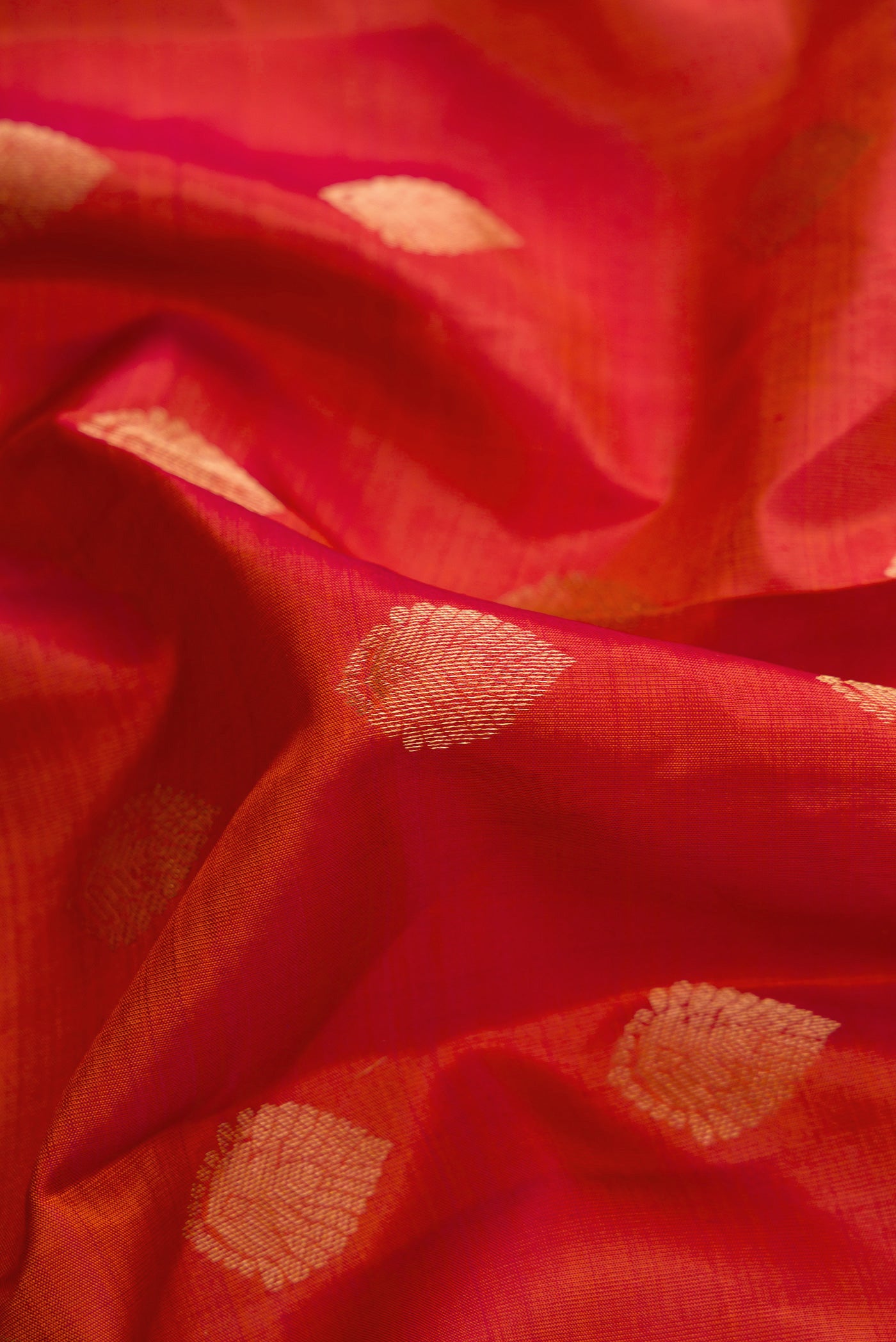 Close up of Brick Orange Dual Tone Kanchipuram Silk Saree with Zari Butta on the body and Thin Zari Line.  displaying folds