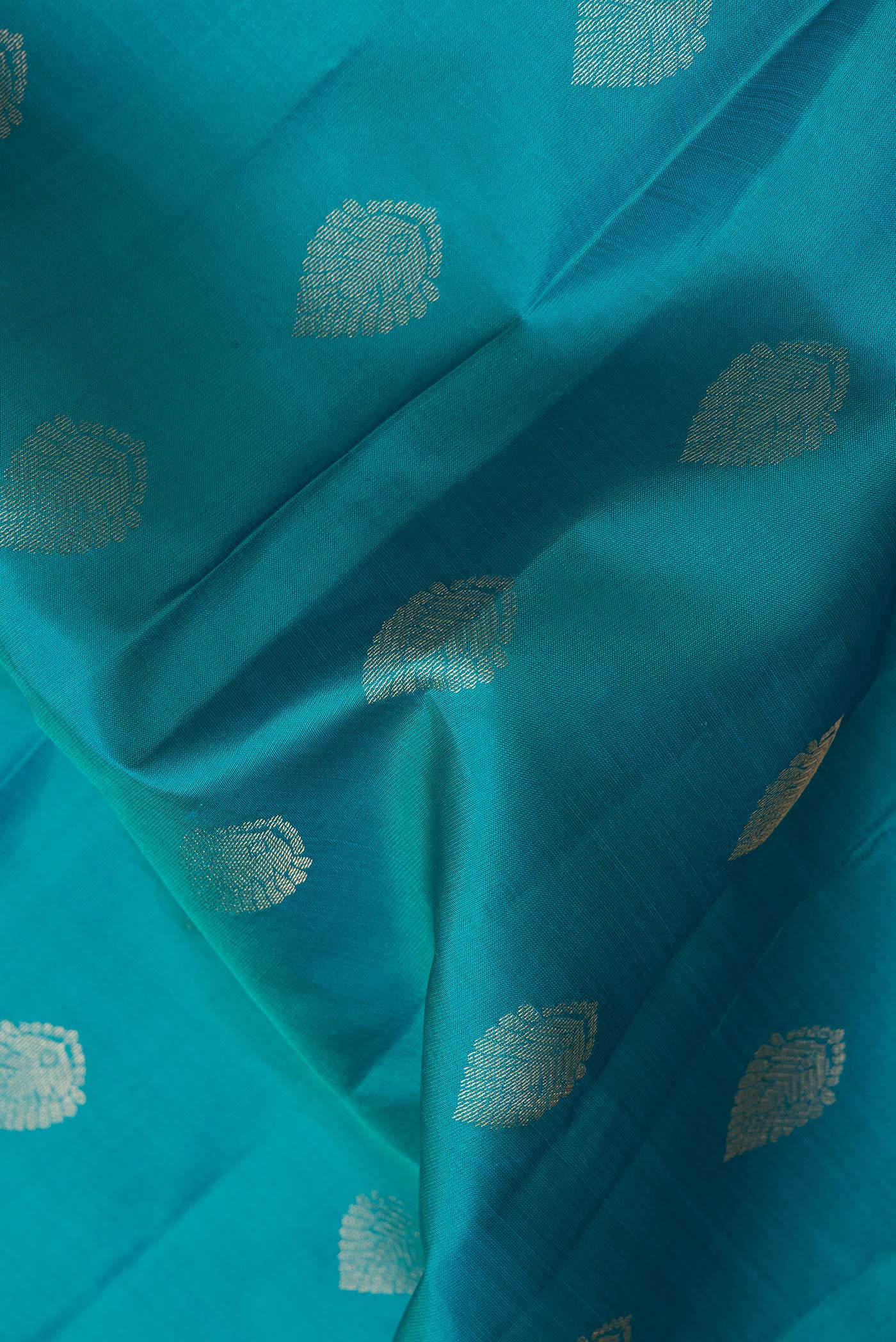 Close up of Peacock Blue Dual Tone Kanchipuram Silk Saree with Zari Butta on the body and Zari Border.  displaying folds