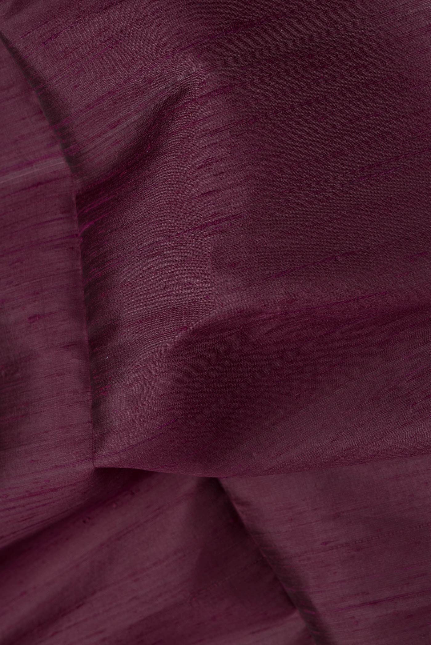 Close up of Burgundy Dual Tone Raw Silk Saree with Plain Body and Zari Border.  displaying folds