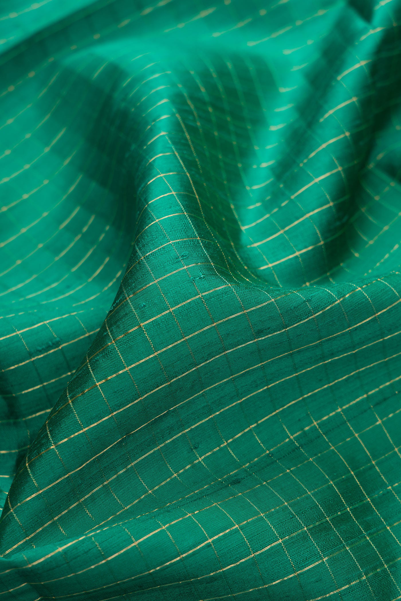 Close up of Green Dual Tone Raw Silk Saree with Checked design on the body and Thin Zari Line.  displaying folds