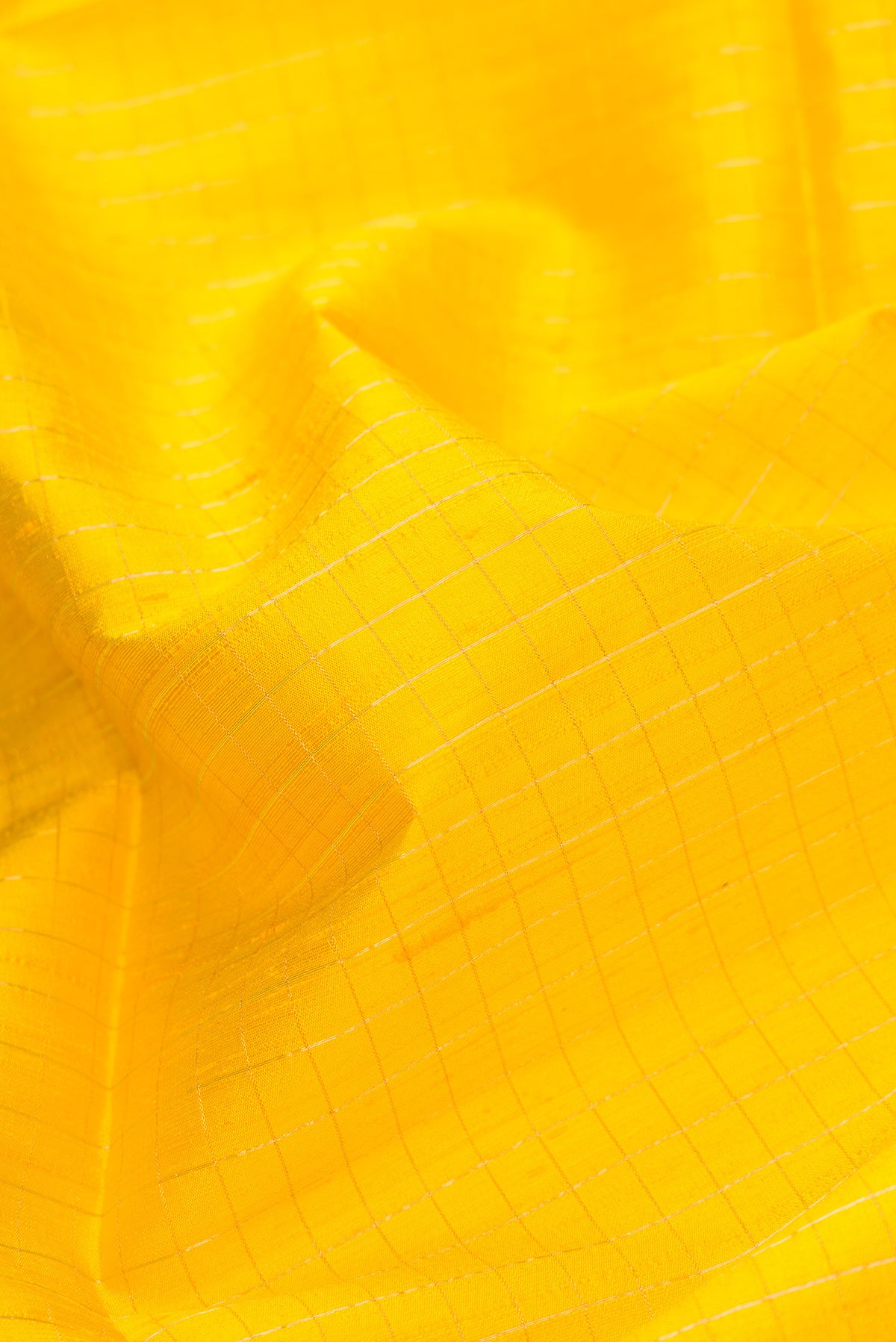 Close up of Yellow Dual Tone Raw Silk Saree with Checked design on the body and Thin Zari Line.  displaying folds