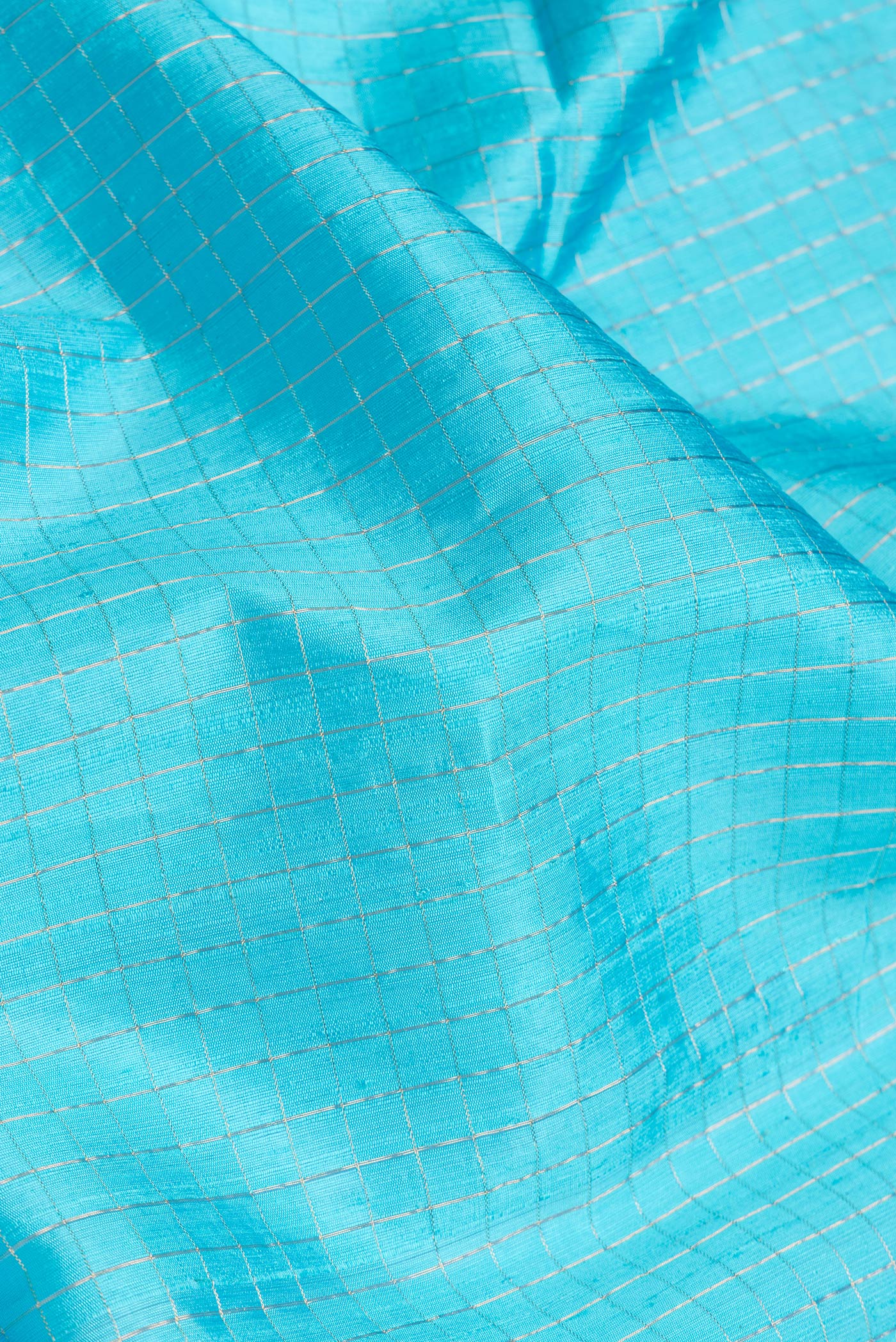 Close up of Sky Blue Dual Tone Raw Silk Saree with Checked design on the body and Zari Border.  displaying folds