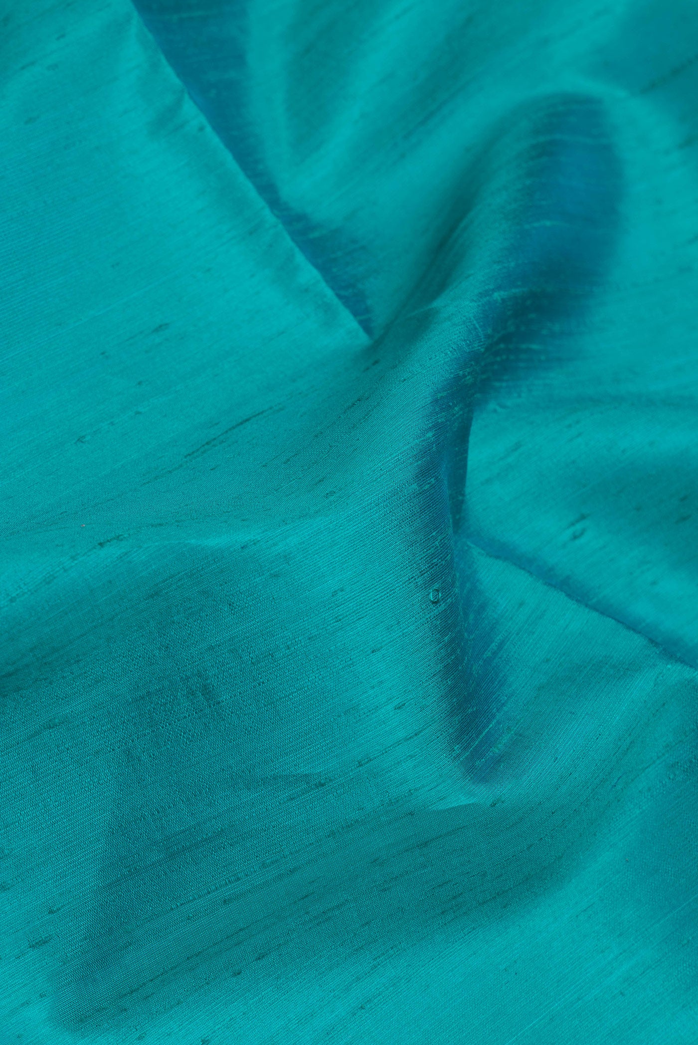 Close up of Sky Blue Dual Tone Raw Silk Saree with Plain Body and Zari Border.  displaying folds