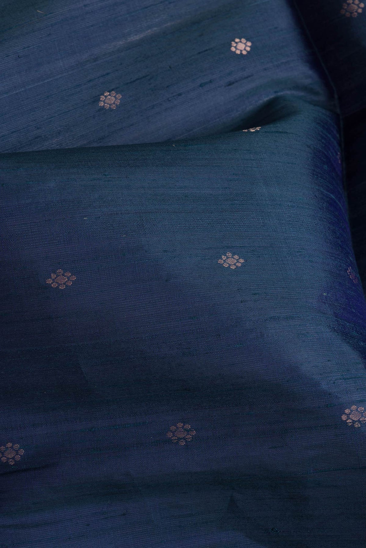 Close up of Peacock Blue Dual Tone Raw Silk Saree with Zari Butta on the body and Thin Zari Line.  displaying folds