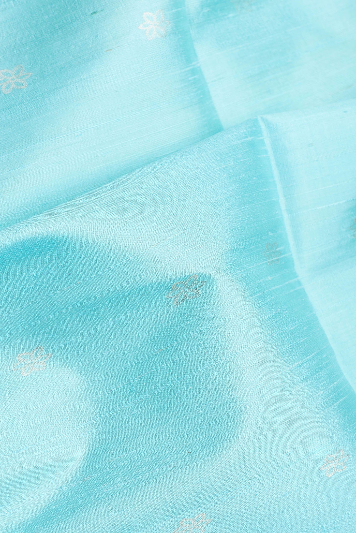 Close up of Sky Blue Dual Tone Raw Silk Saree with Zari Butta on the body and Zari Border.  displaying folds