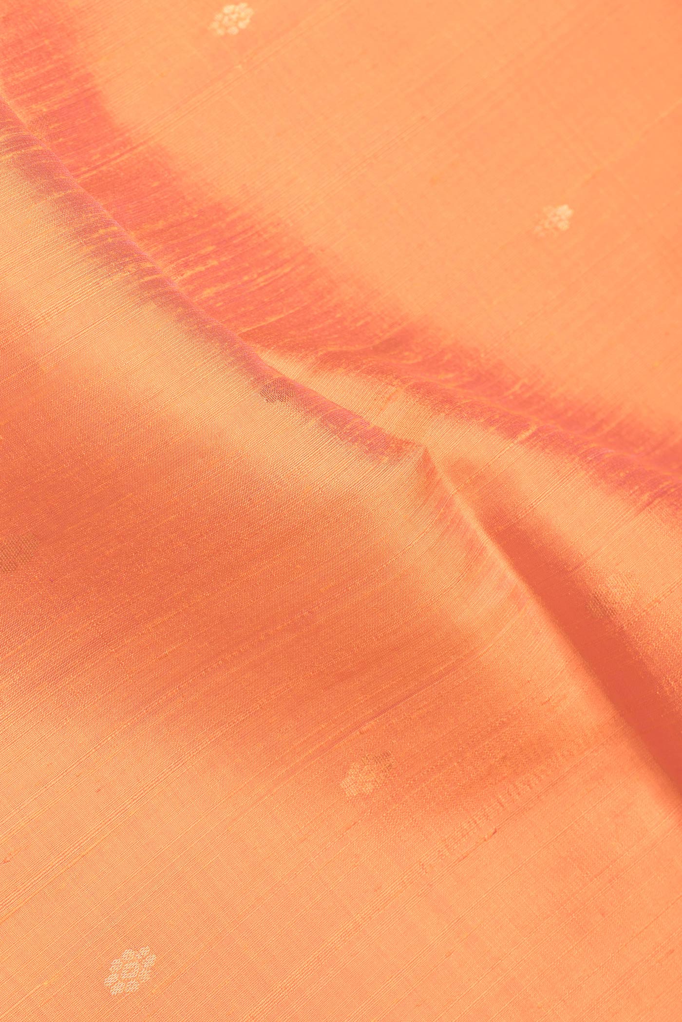 Close up of Orange Dual Tone Raw Silk Saree with Zari Butta on the body and Zari Border.  displaying folds
