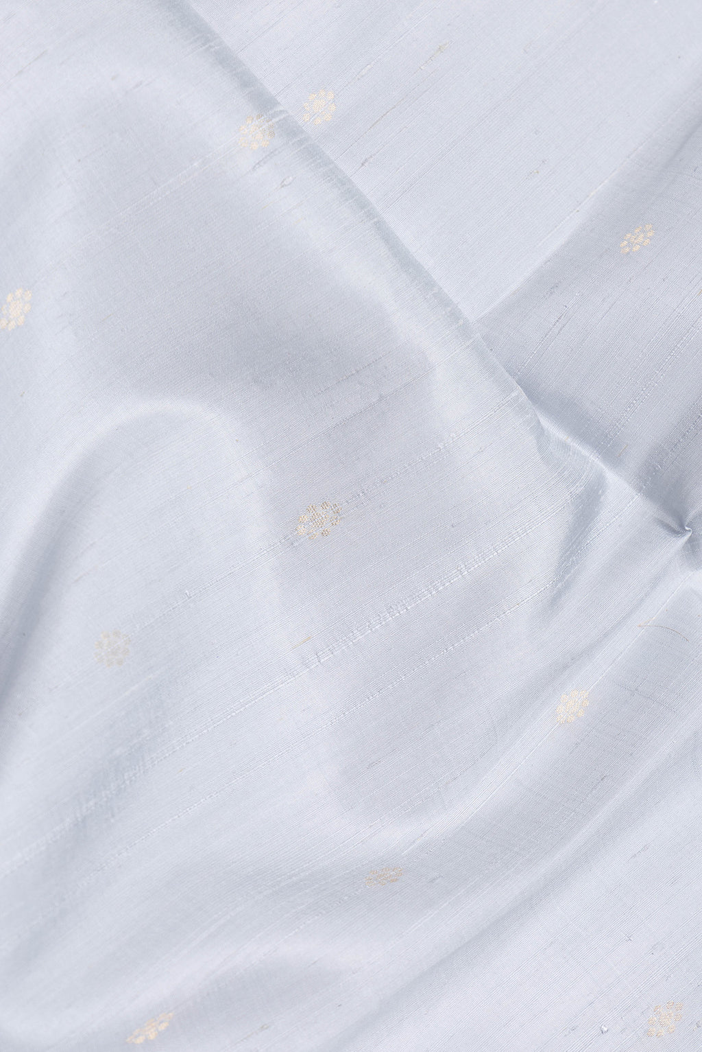 Close up of Grey Dual Tone Raw Silk Saree with Zari Butta on the body and Zari Border.  displaying folds