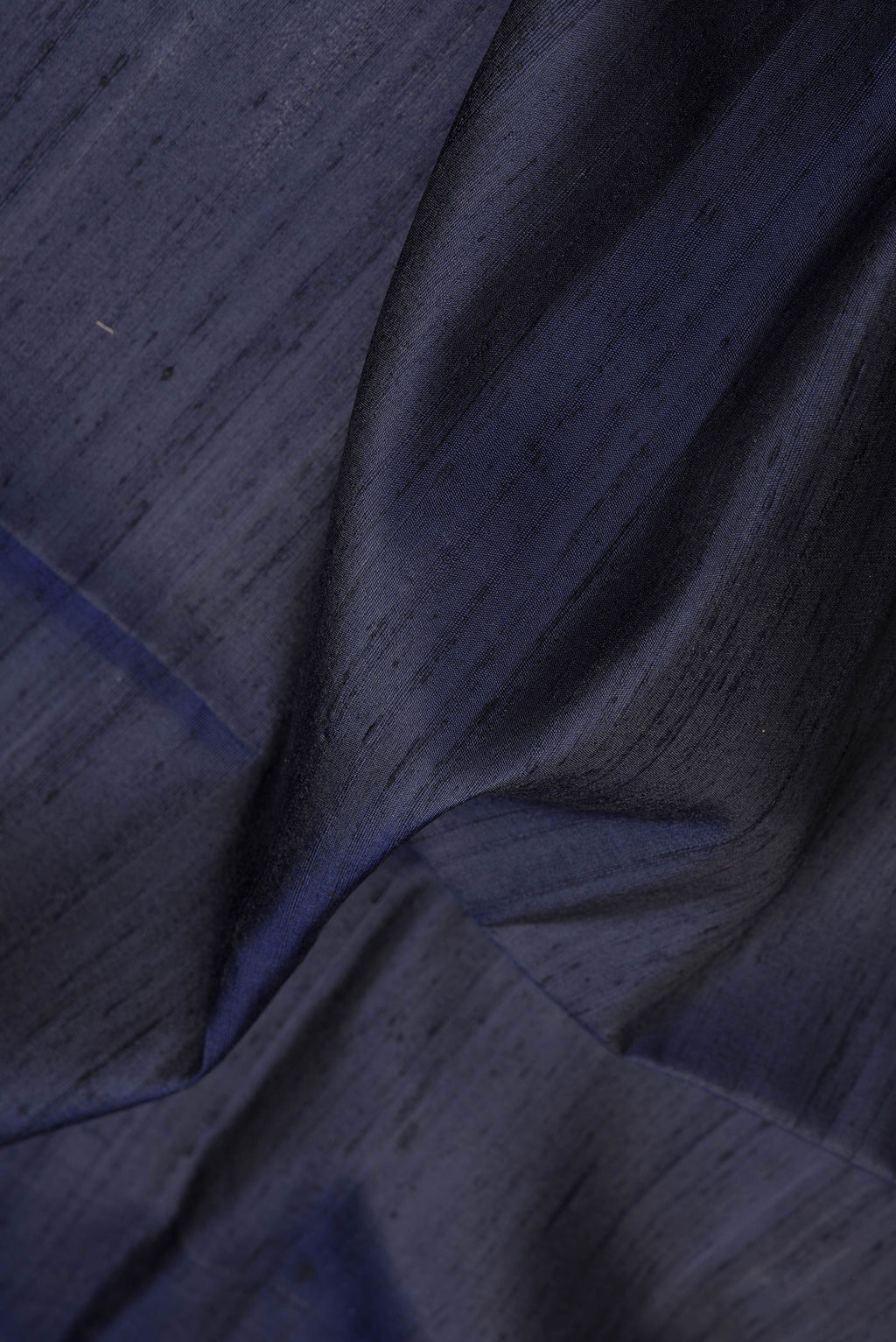 Close up of Navy Blue Dual Tone Raw Silk Saree with Plain Body and Fancy Border.  displaying folds