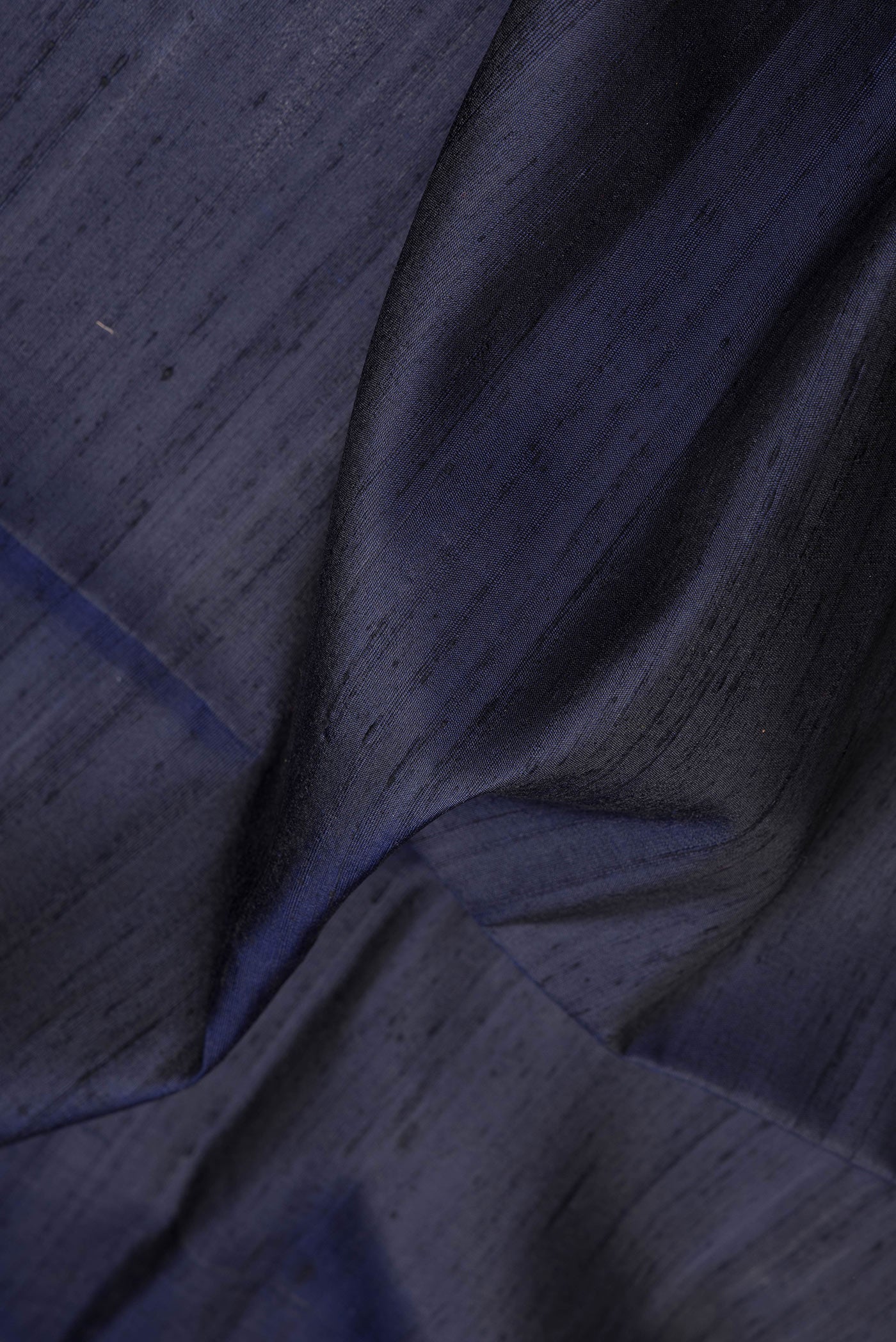 Close up of Navy Blue Dual Tone Raw Silk Saree with Plain Body and Fancy Border.  displaying folds