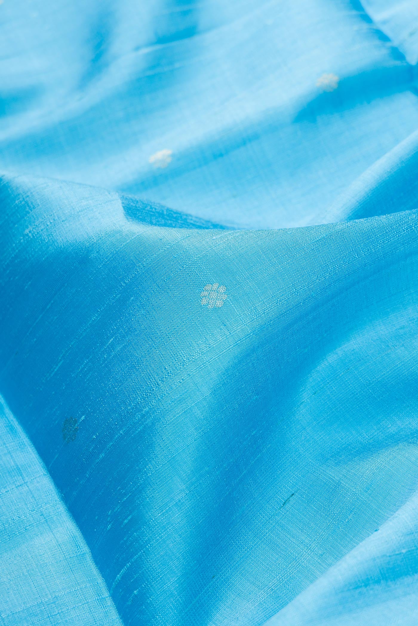 Close up of Sky Blue Dual Tone Raw Silk Saree with Zari Butta on the body and Fancy Border.  displaying folds