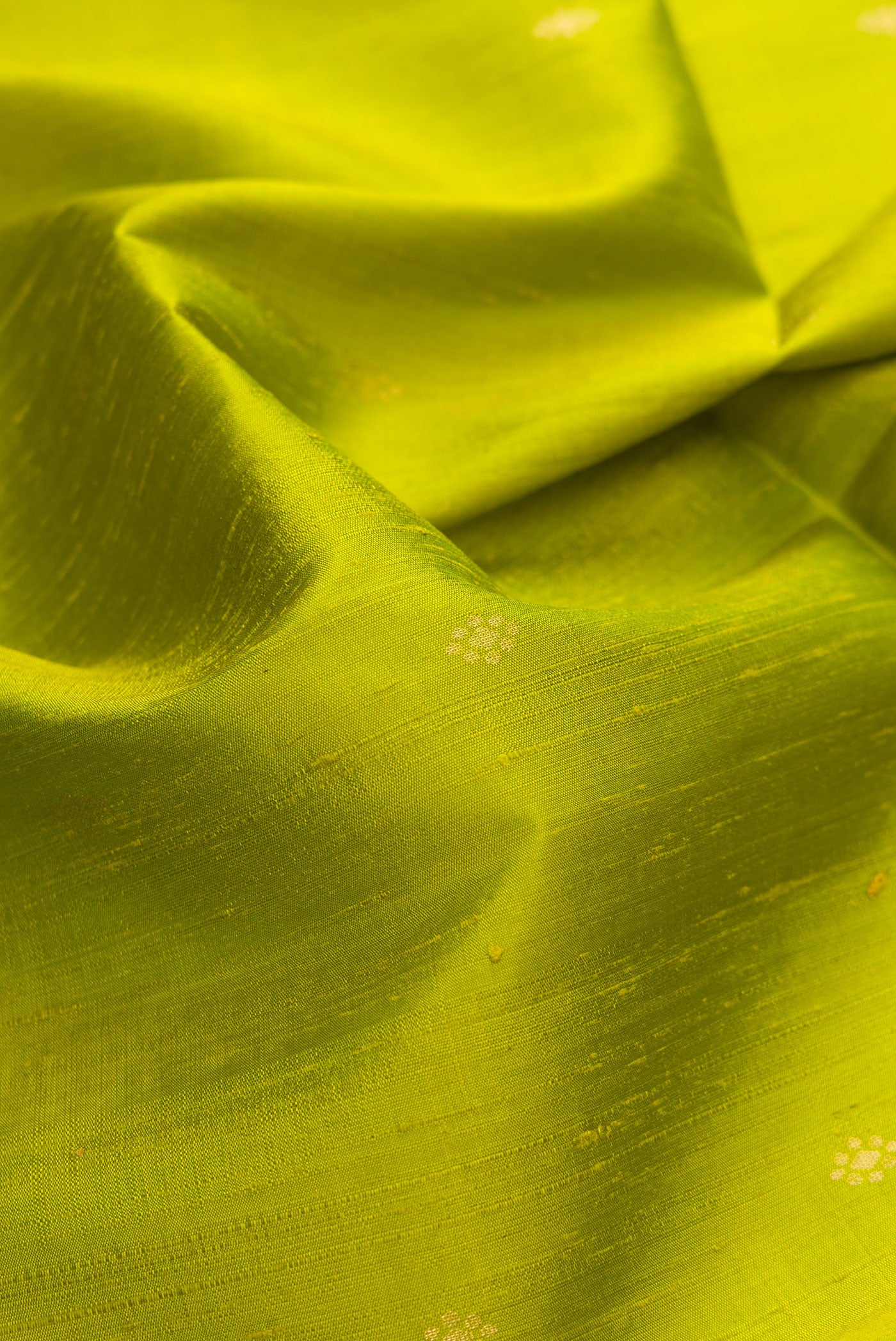 Close up of Parrot Green Dual Tone Raw Silk Saree with Zari Butta on the body and Fancy Border.  displaying folds