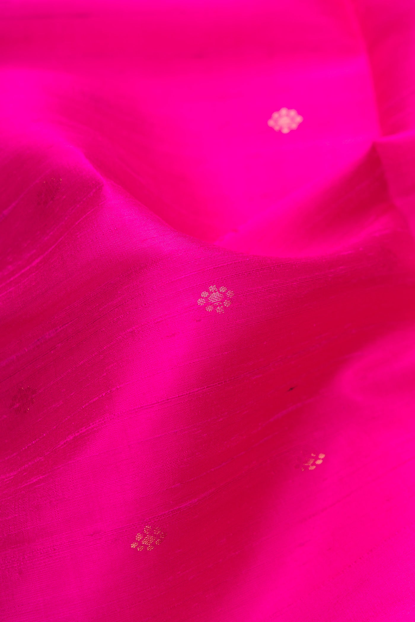 Close up of Magenta Dual Tone Raw Silk Saree with Zari Butta on the body and Zari Border.  displaying folds