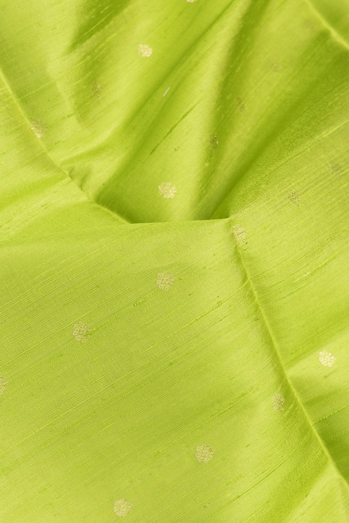 Close up of Parrot Green Dual Tone Raw Silk Saree with Zari Butta on the body and Zari Border.  displaying folds