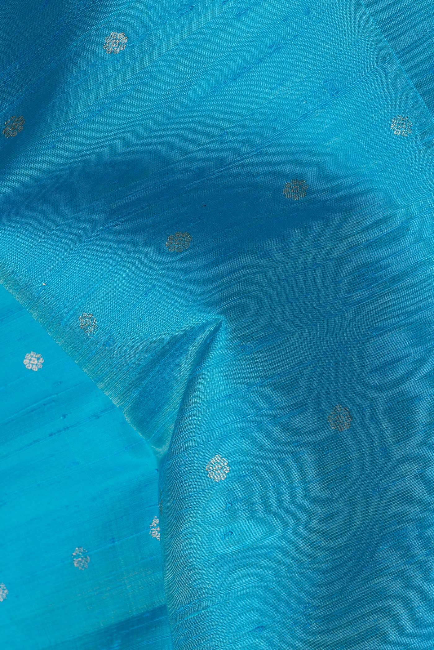 Close up of Sky Blue Dual Tone Raw Silk Saree with Zari Butta on the body and Zari Border.  displaying folds